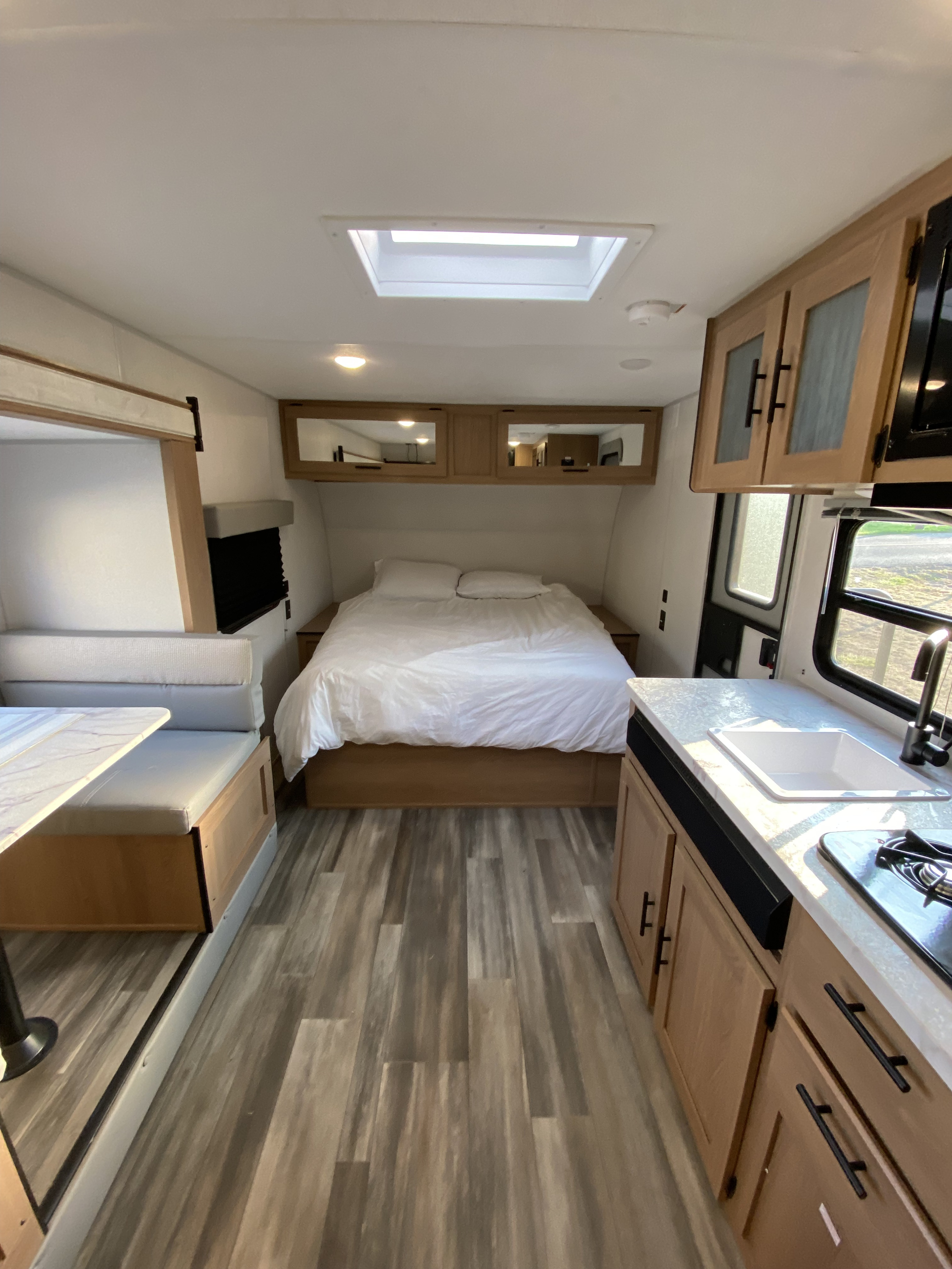 Modern rv rental interior with a bed, kitchen, dinette, and bright skylight.. Forest River Avenger 2022