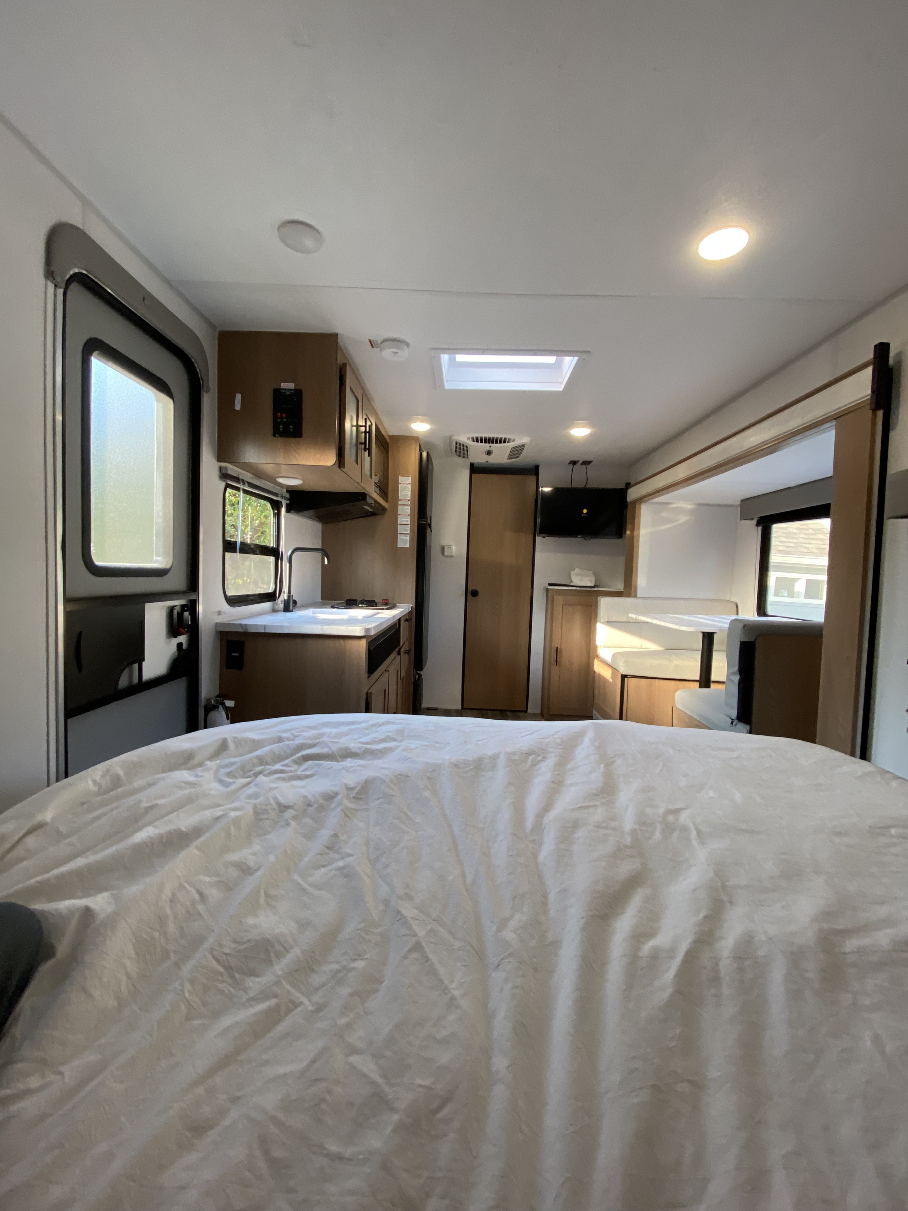 Inside a bright RV rental: a modern interior featuring the kitchen, dinette area, and a comfortable sleeping space.. Forest River Avenger 2022