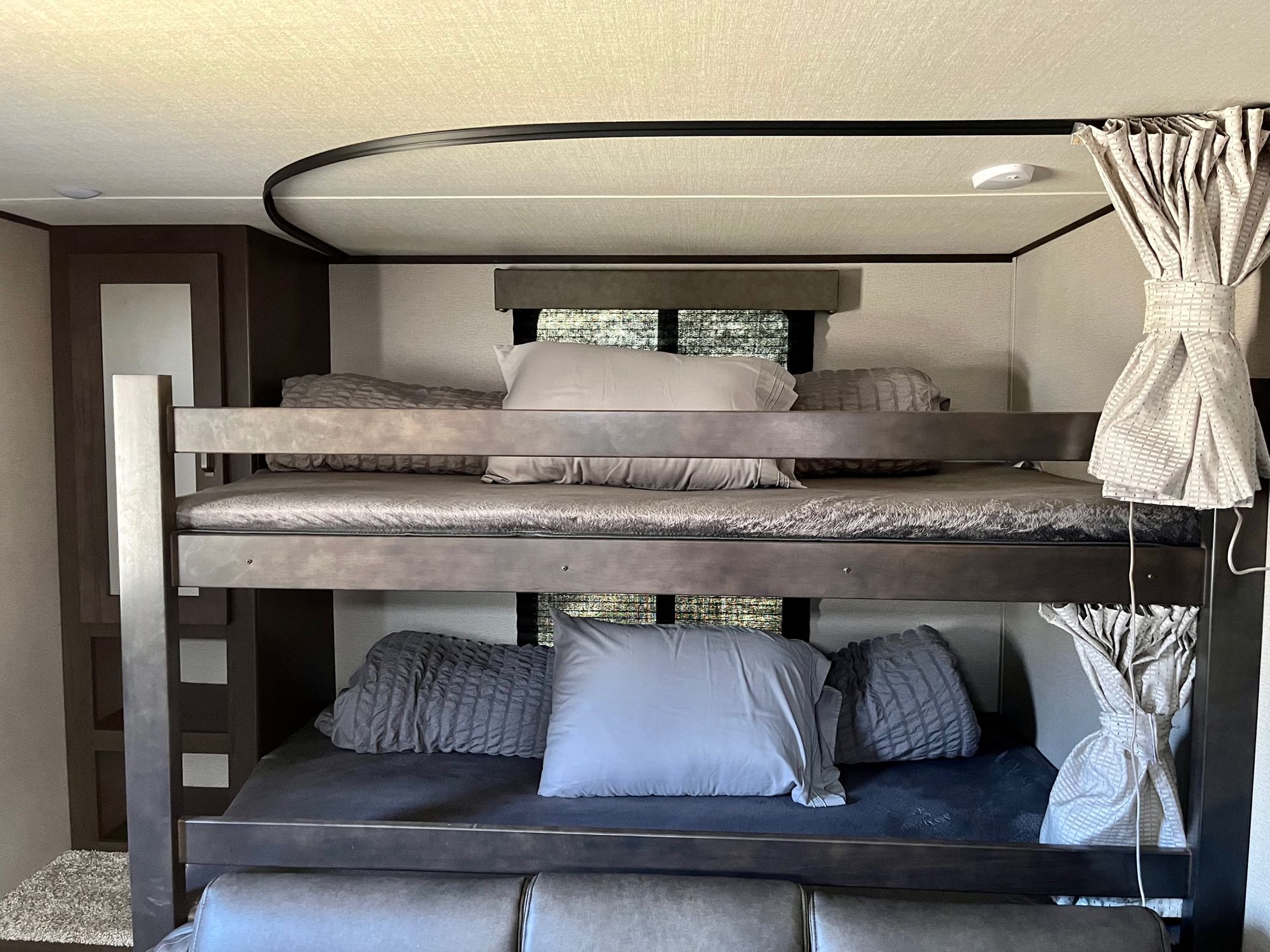Cozy bunk beds inside an RV rental, complete with soft pillows and bedding.. Grand Design Transcend Xplor 2022