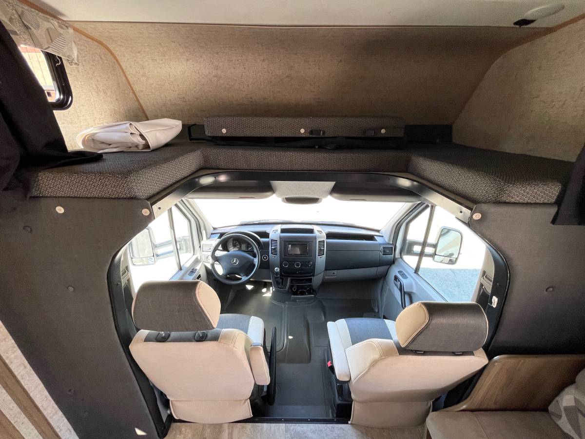 RV rental interior: view of the front cabin with two beige/gray seats and a large overhead sleeping bunk.. Forest River Coachmen Prism 2018