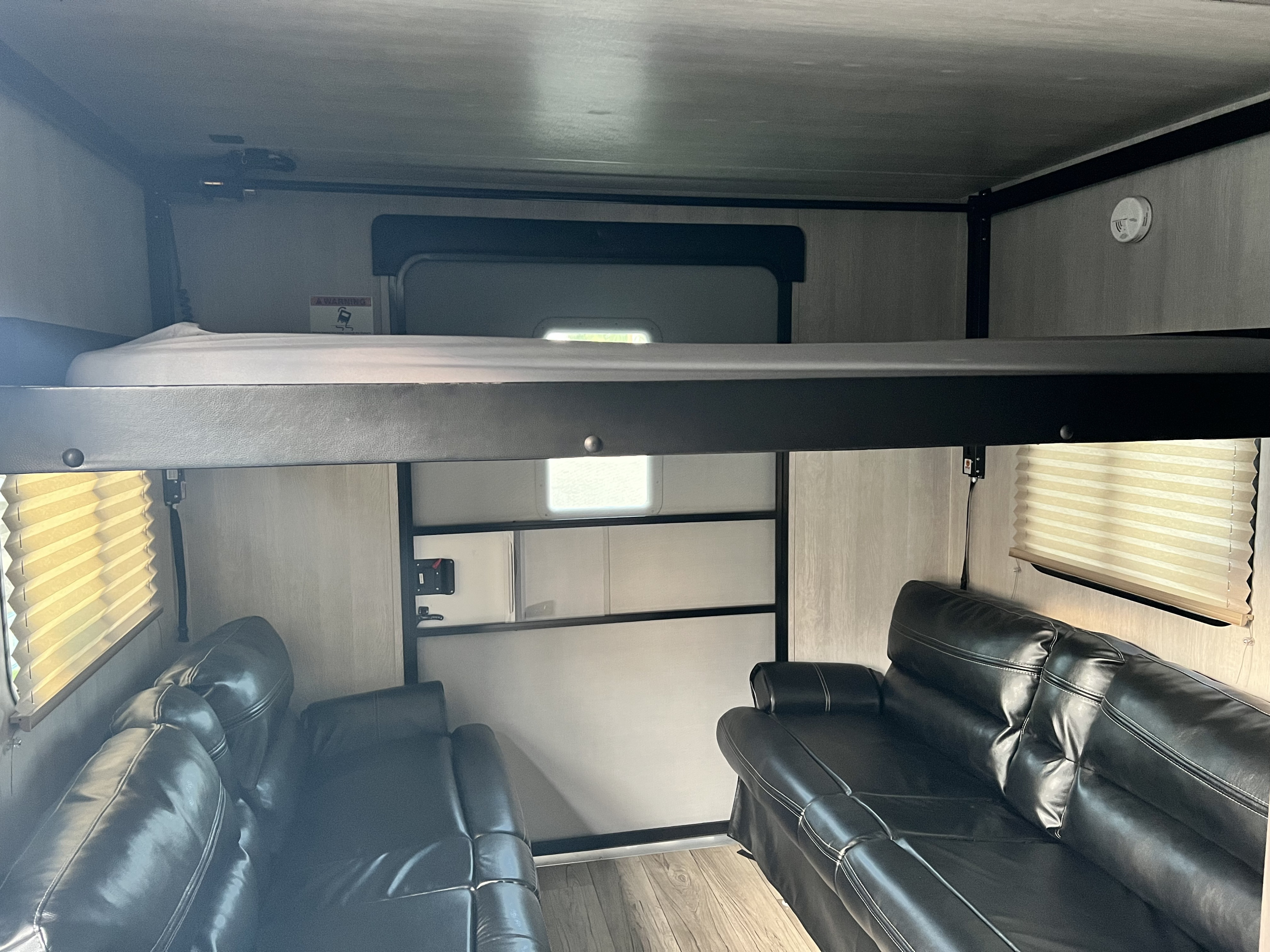 RV rental interior: an upper bunk bed and two black leather sofas provide comfortable living space.. Genesis Supreme Rv Genesis Supreme 2023