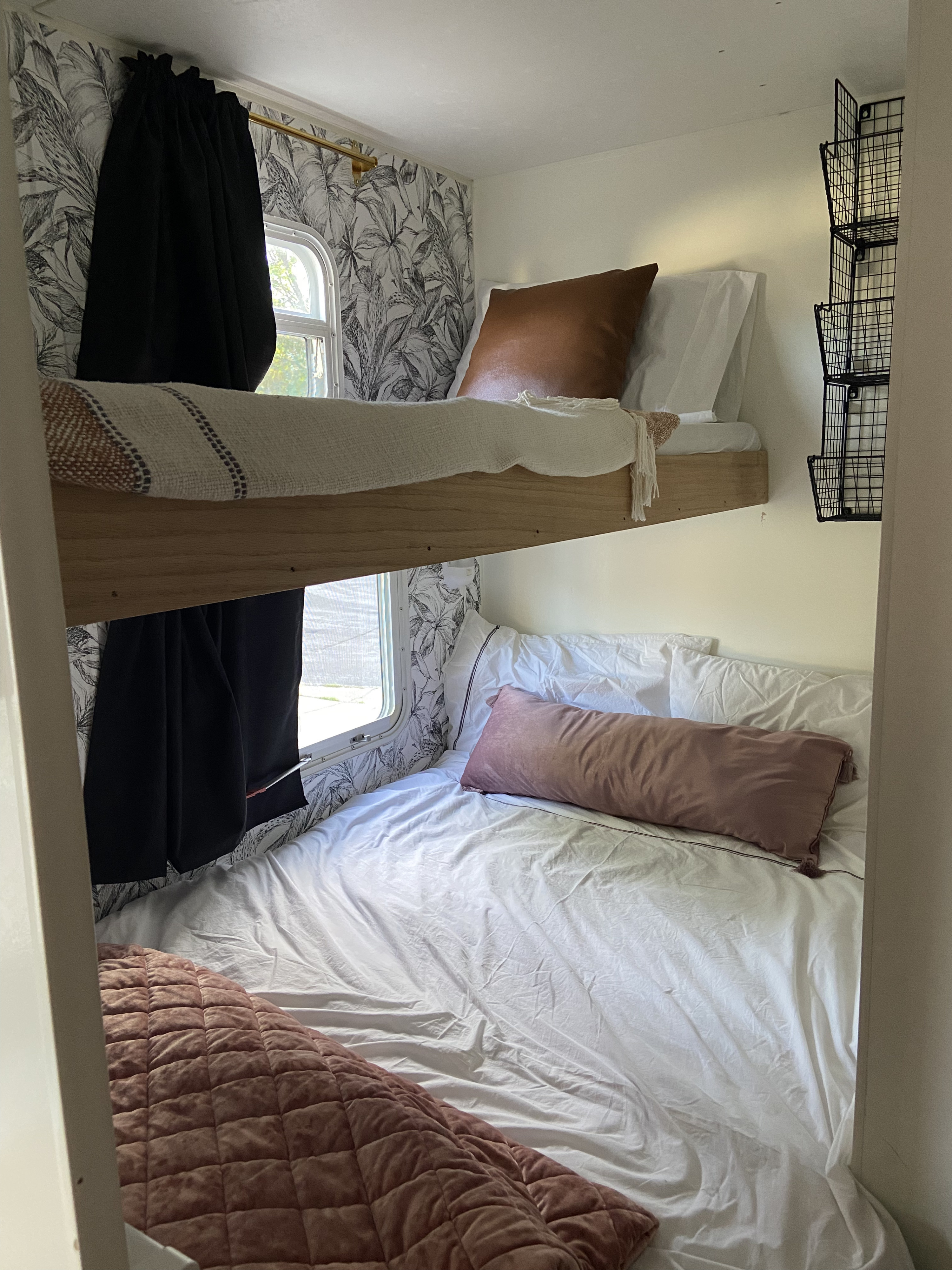 Experience cozy RV rental living: detailed bunk beds with tropical wallpaper, black curtains, and a smart wall storage unit.. Jayco Jay Flight 2007