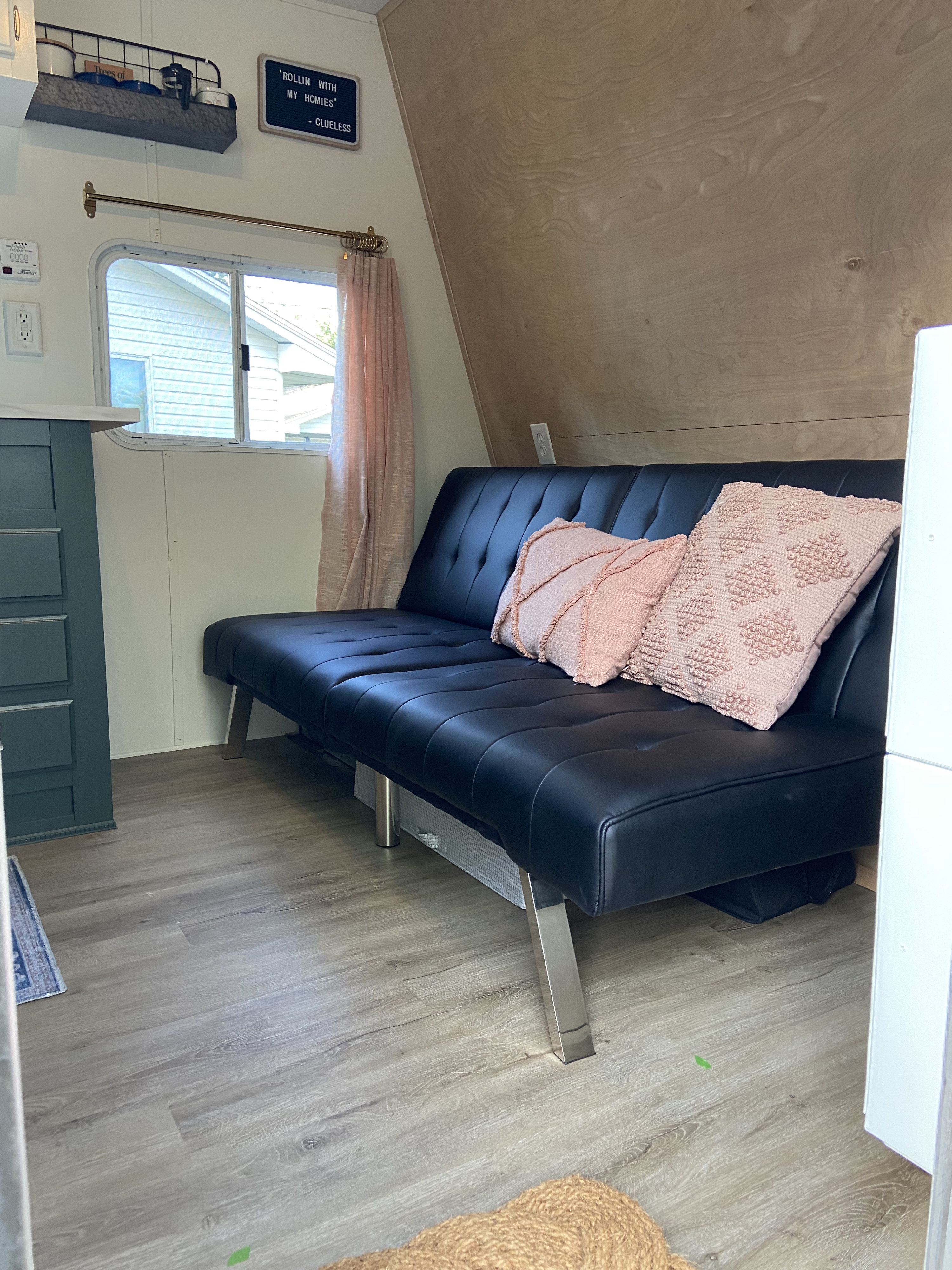 Inviting RV rental interior: black sofa bed, pink pillows, light wood walls & vinyl plank floors. Perfect for road trips!. Jayco Jay Flight 2007
