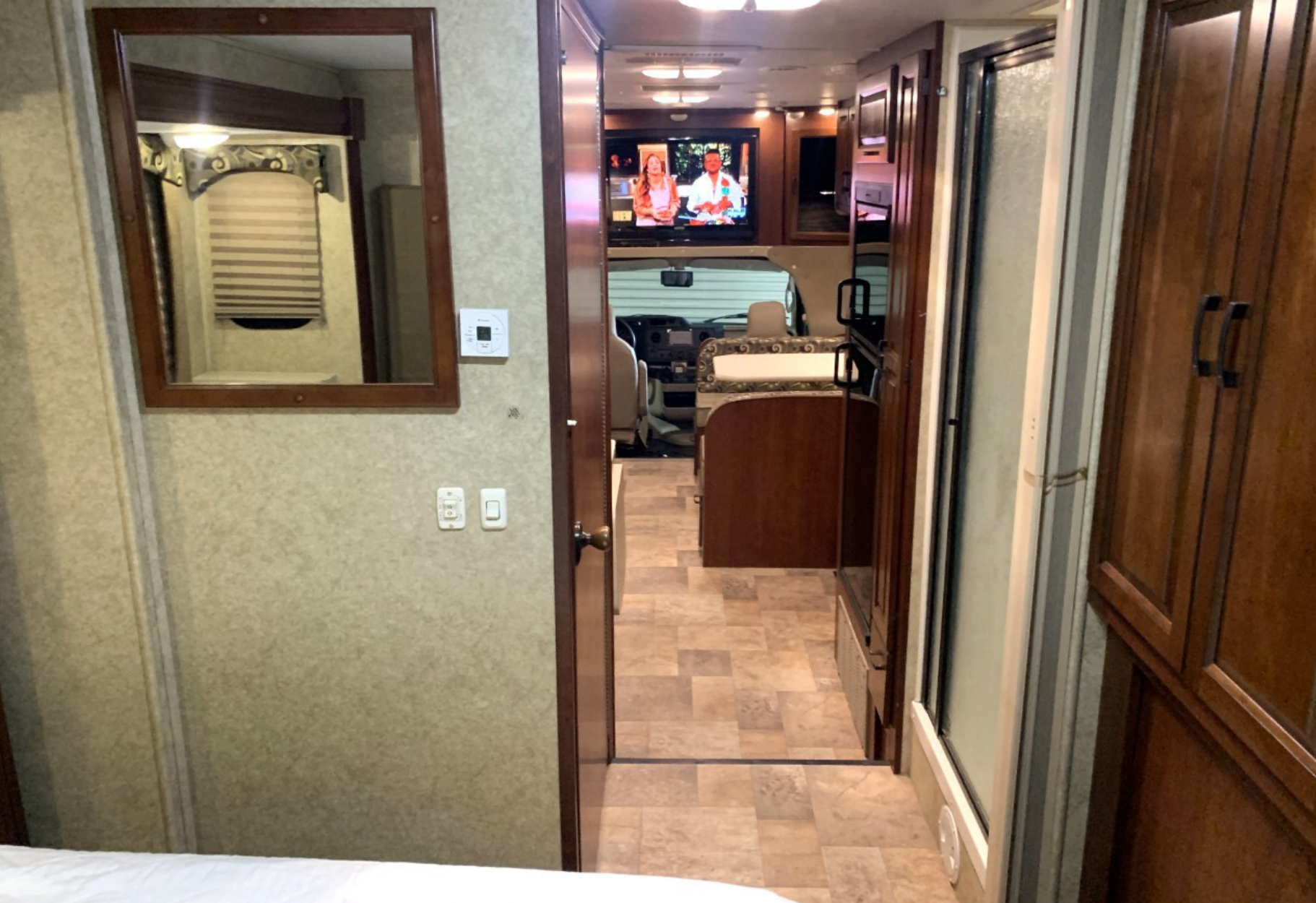 Spacious RV rental interior: View from bedroom showing mirror, to living area, kitchen, cockpit. Includes TV and shower stall.. Forest River Sunseeker 2013