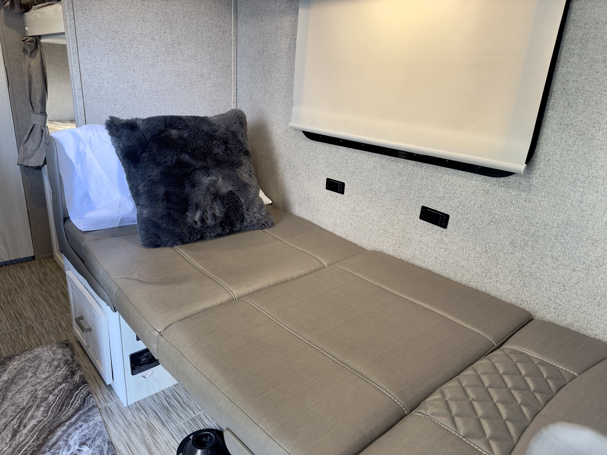 RV rental: Light-toned interior with a long, taupe upholstered dinette bed, dark pillow, pull-down blind, and base storage.. Forest River Rockwood GeoPro 2019