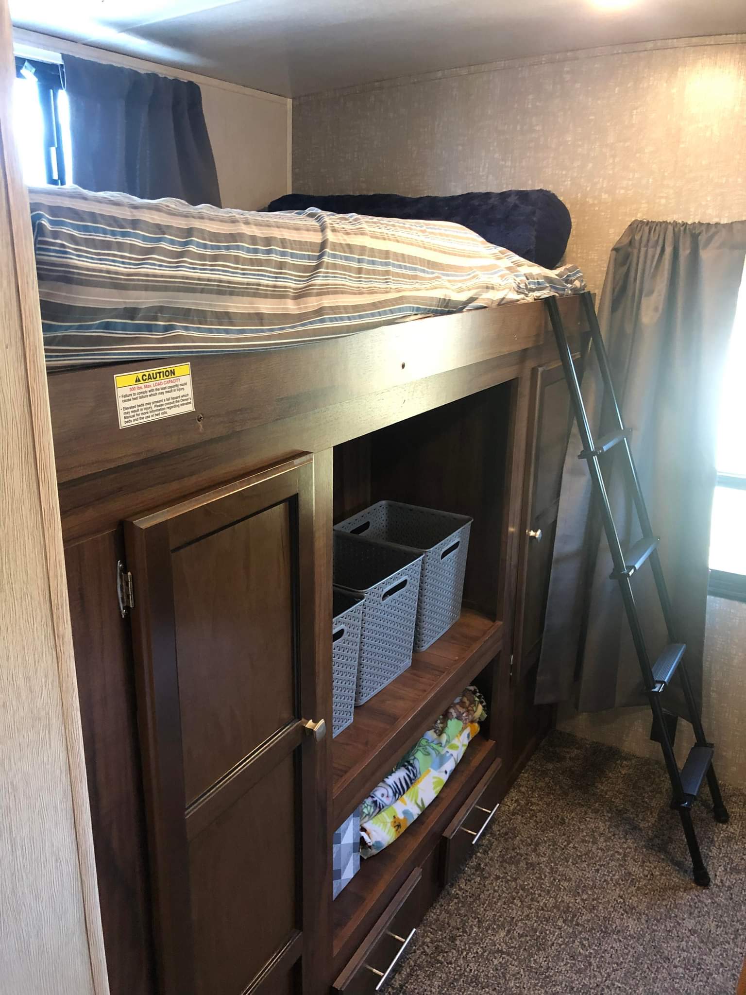 Cozy RV rental interior with a bunk bed, storage cabinets, and a ladder, ideal for travel accommodations.. Heartland RVs Mallard 2019