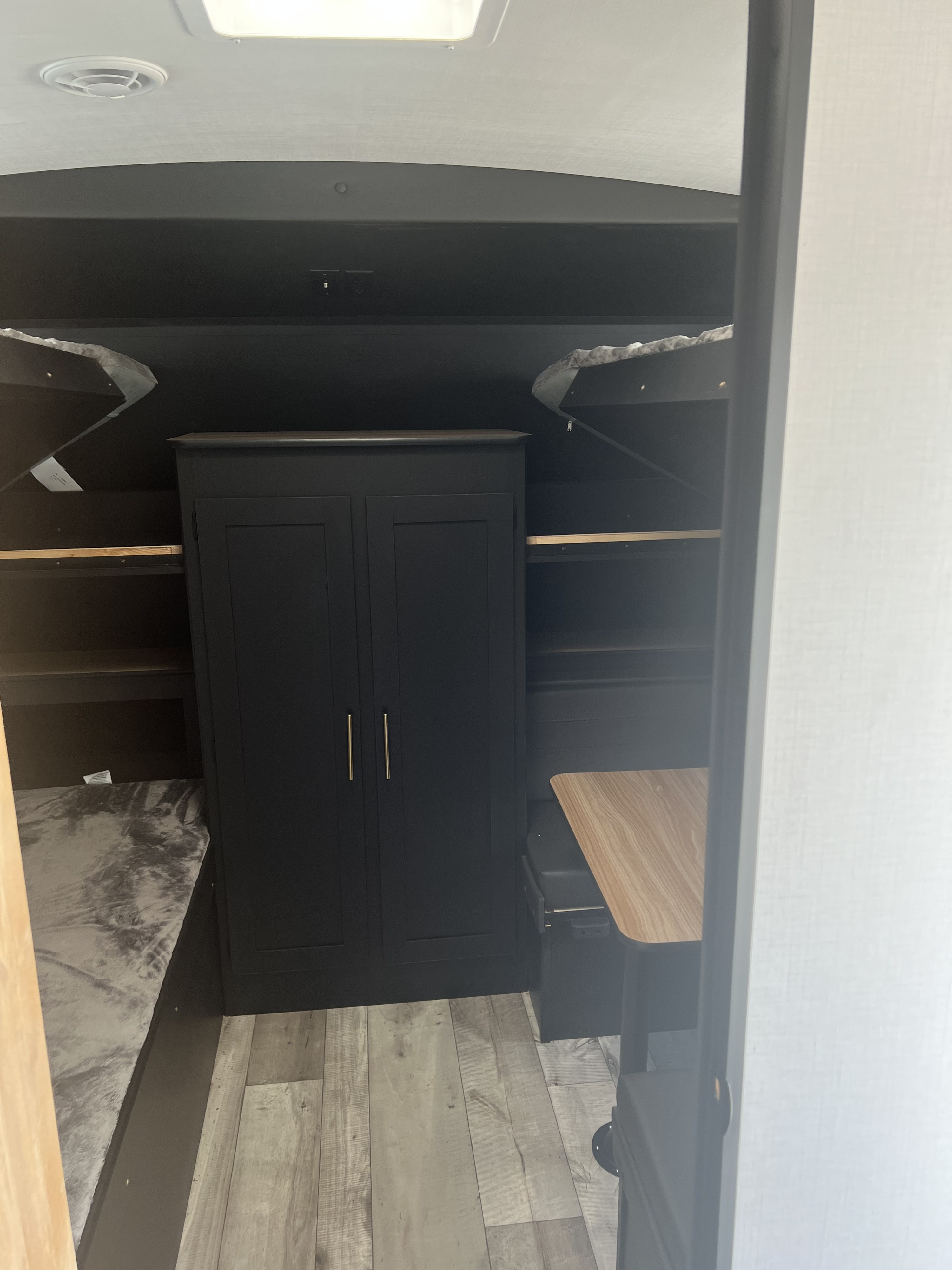 RV rental interior shows bunk beds, central wardrobe, and dinette area, featuring a cozy, functional layout.. Keystone RV Springdale 2022