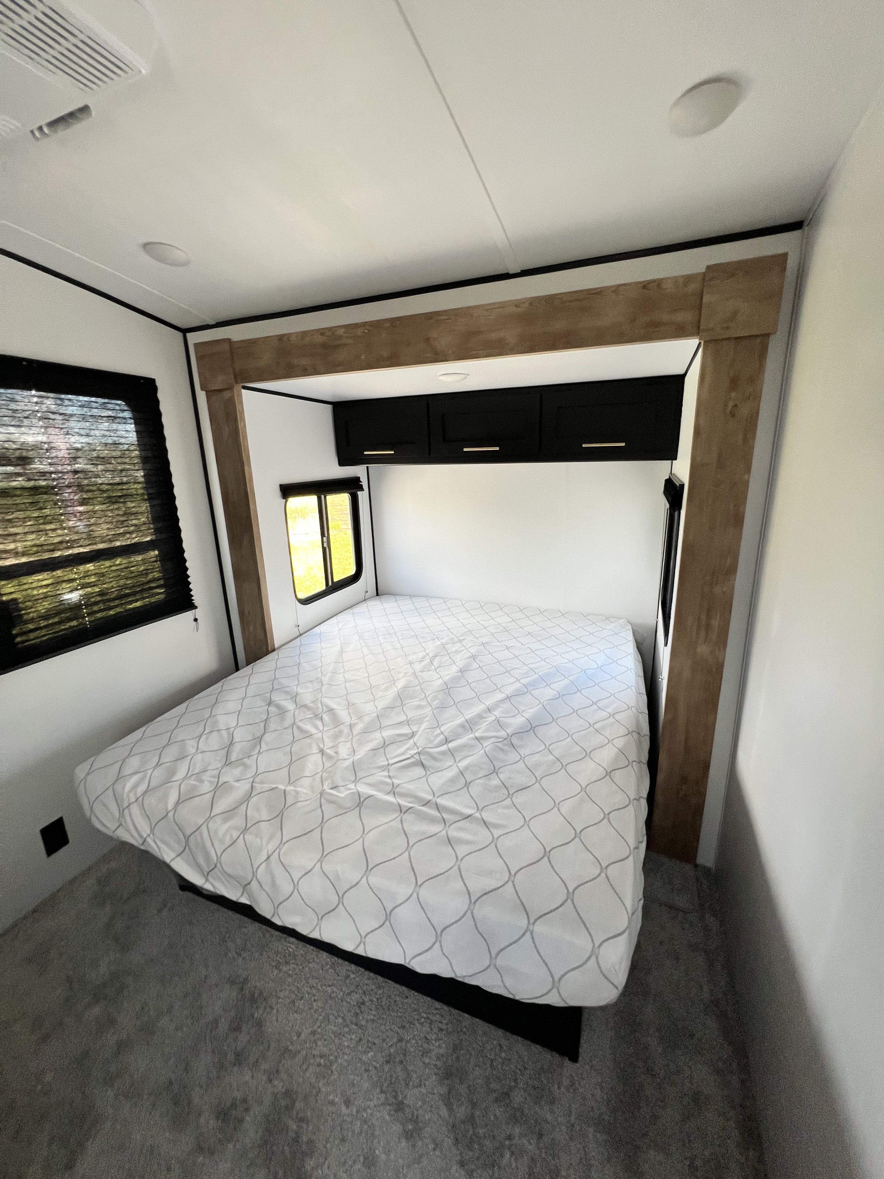 Modern RV rental bedroom with spacious bed, dark cabinets, and light wood trim. Ideal for comfortable travel.. Keystone RV Springdale 2022