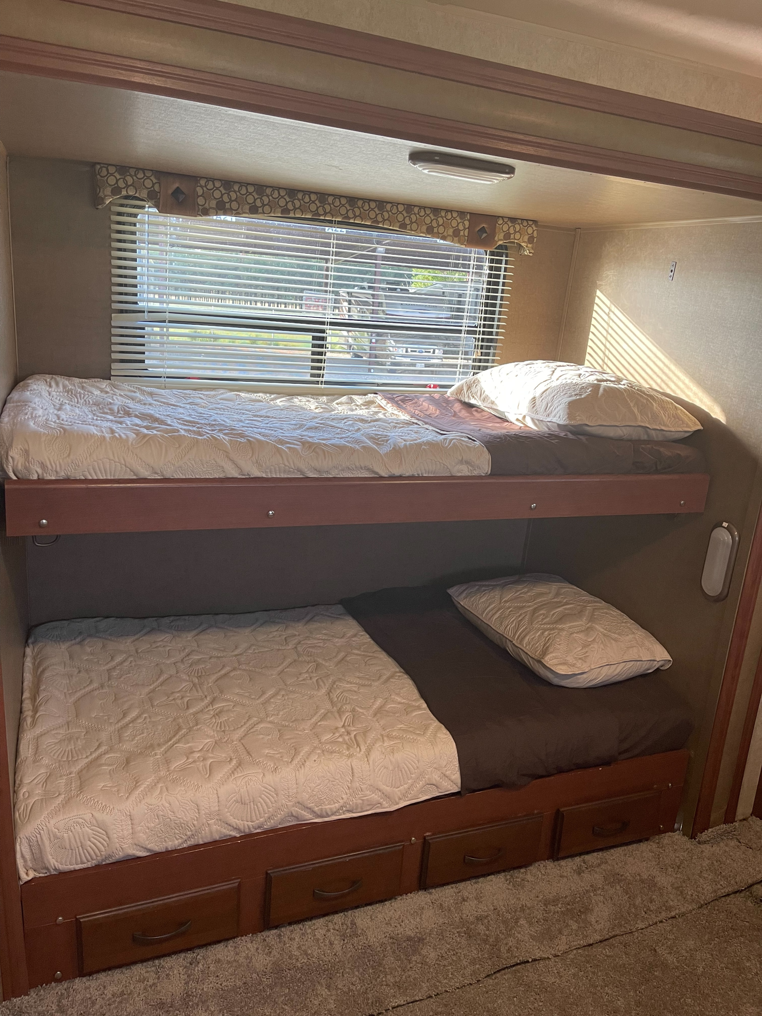 Inside a comfortable RV rental: bunk beds, natural light from blinds, and built-in storage drawers below.. Palomino Puma 2015