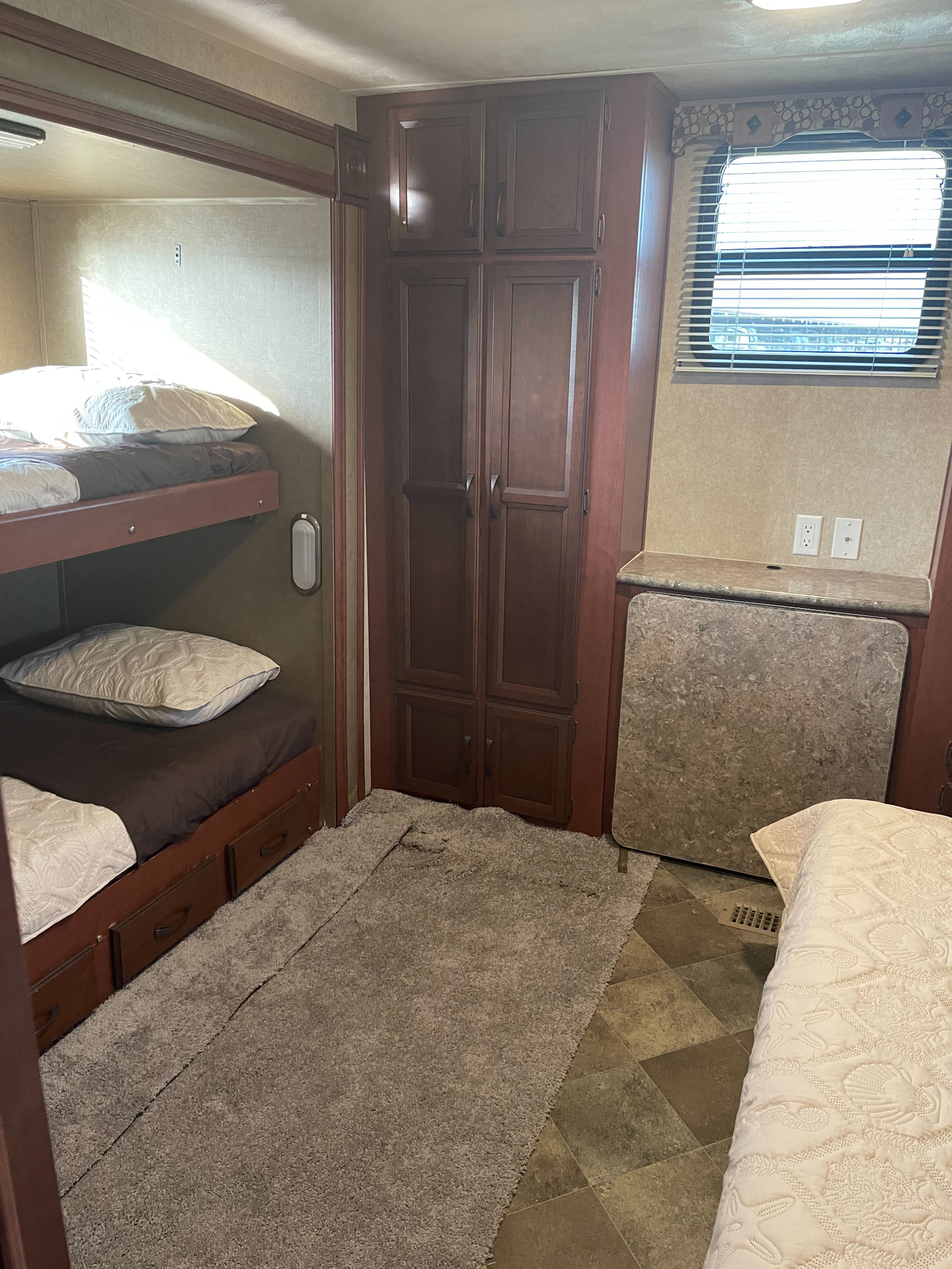 RV rental interior featuring cozy bunk beds, spacious dark wood cabinets, and a counter with a pull-out table.. Palomino Puma 2015