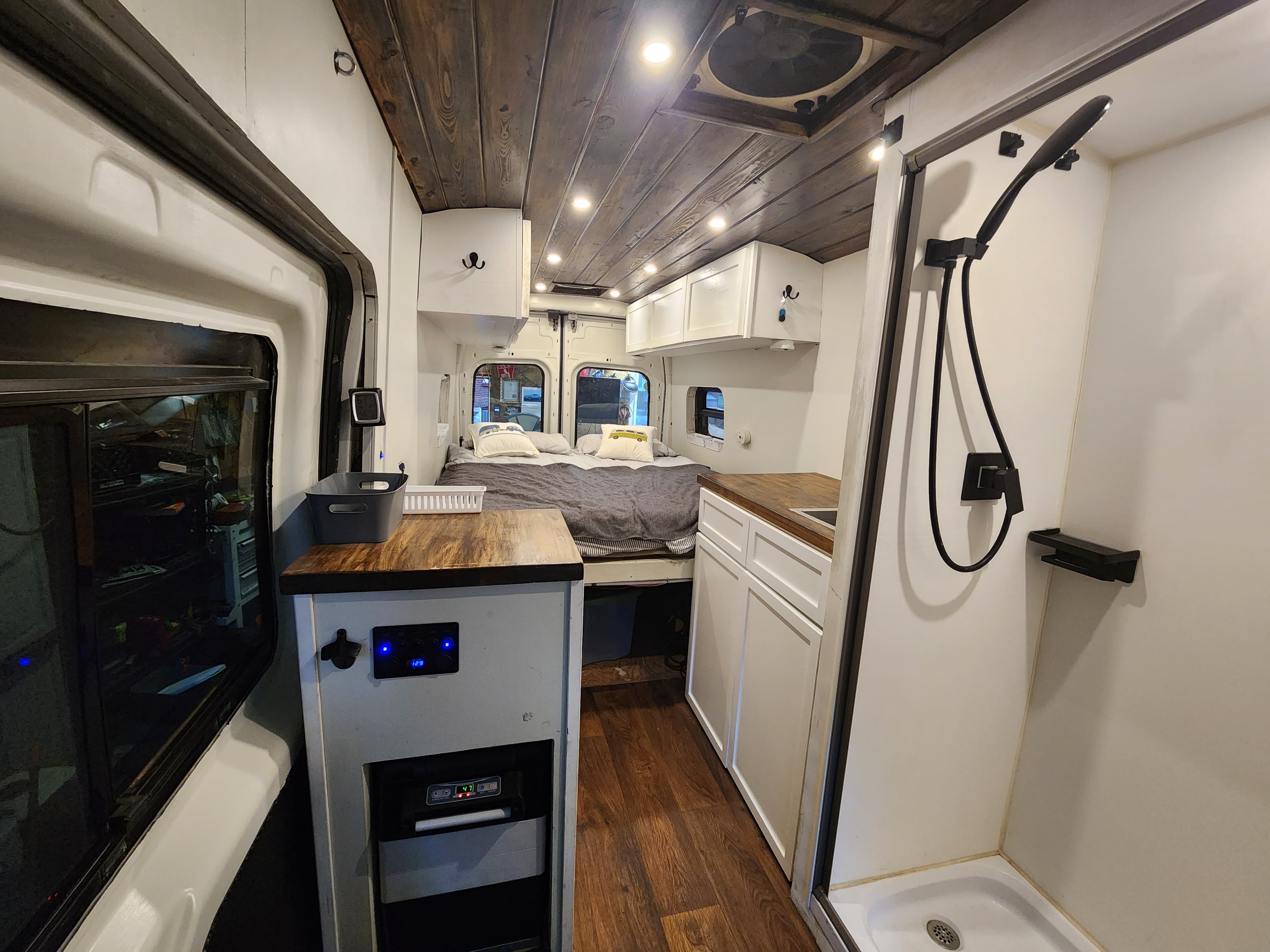 Modern RV rental interior: bed, kitchen, shower, and wood ceiling. Bright, functional camper van for travel.. Ford Custom Transit 2016