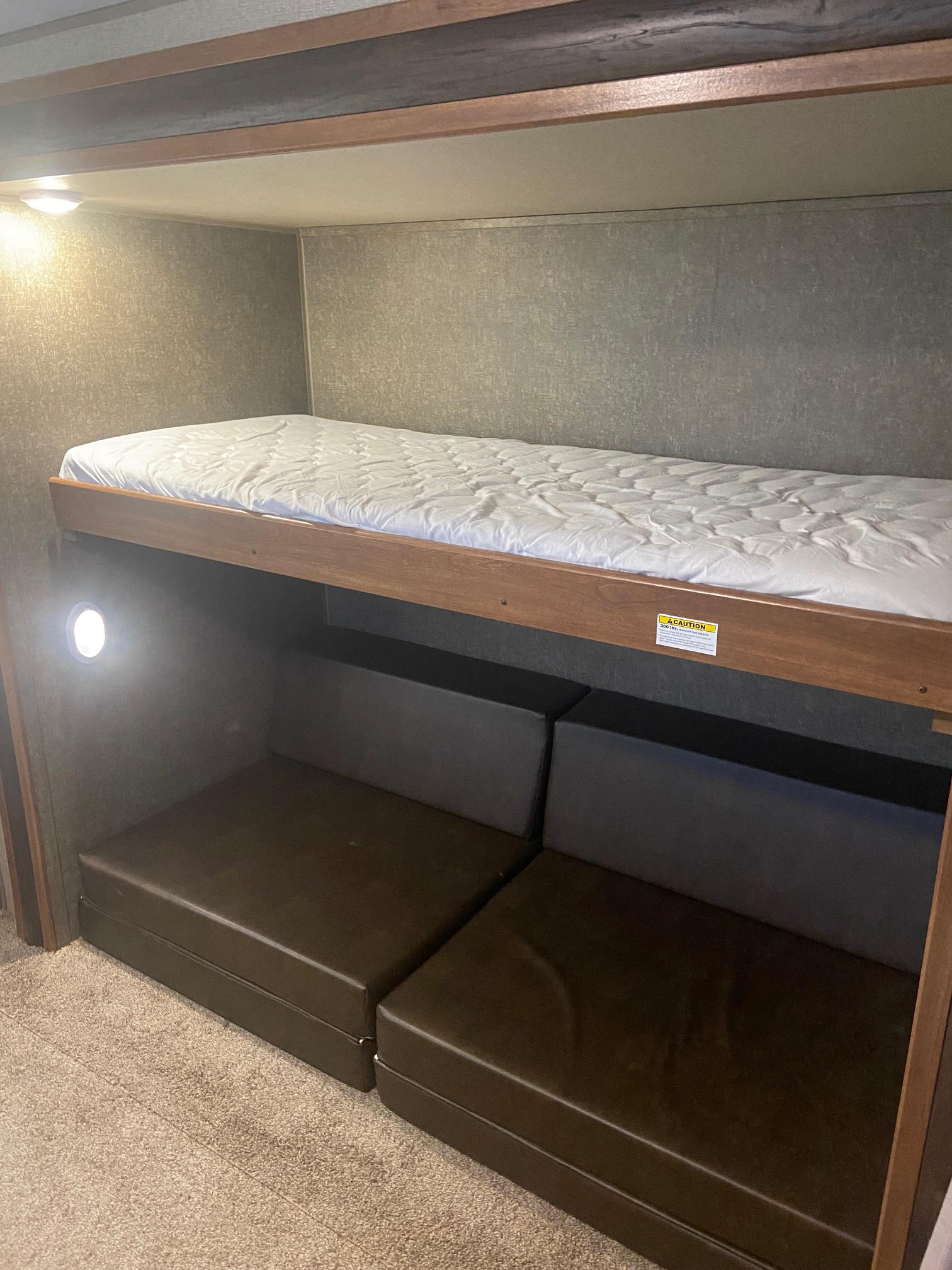 Compact RV rental bunk beds: upper mattress, lower seating/convertible bed, and an interior light.. Keystone RV Springdale 2018
