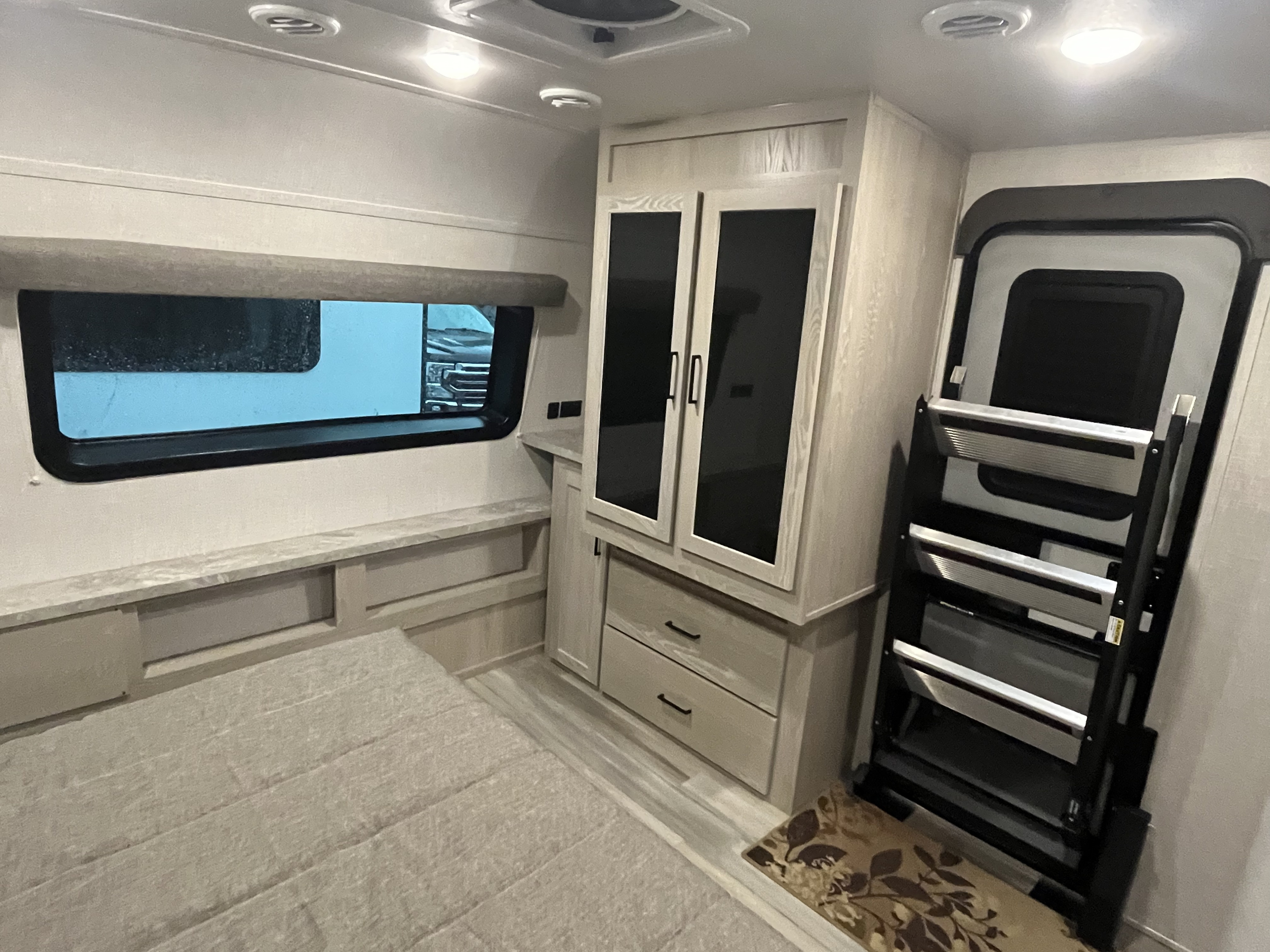 Experience comfort in this RV rental's bedroom, featuring a window, bed, light-toned cabinets, and sturdy entry steps.. Forest River Rockwood Ultra Lite 2021