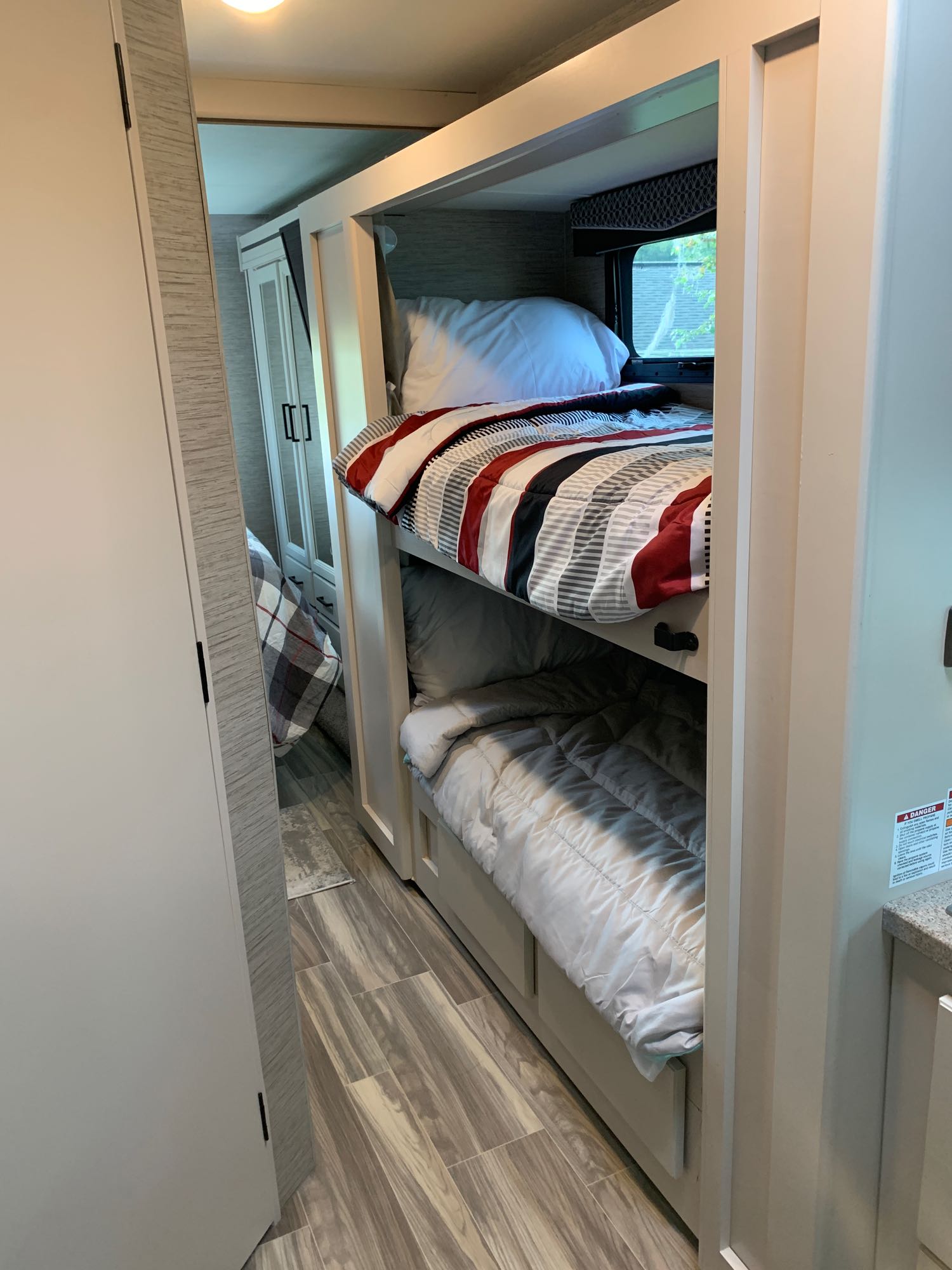 Experience comfort in this RV rental's bunk bed area. Features striped bedding on top, solid on bottom, and view to main bed.. Thor Four Winds 2022