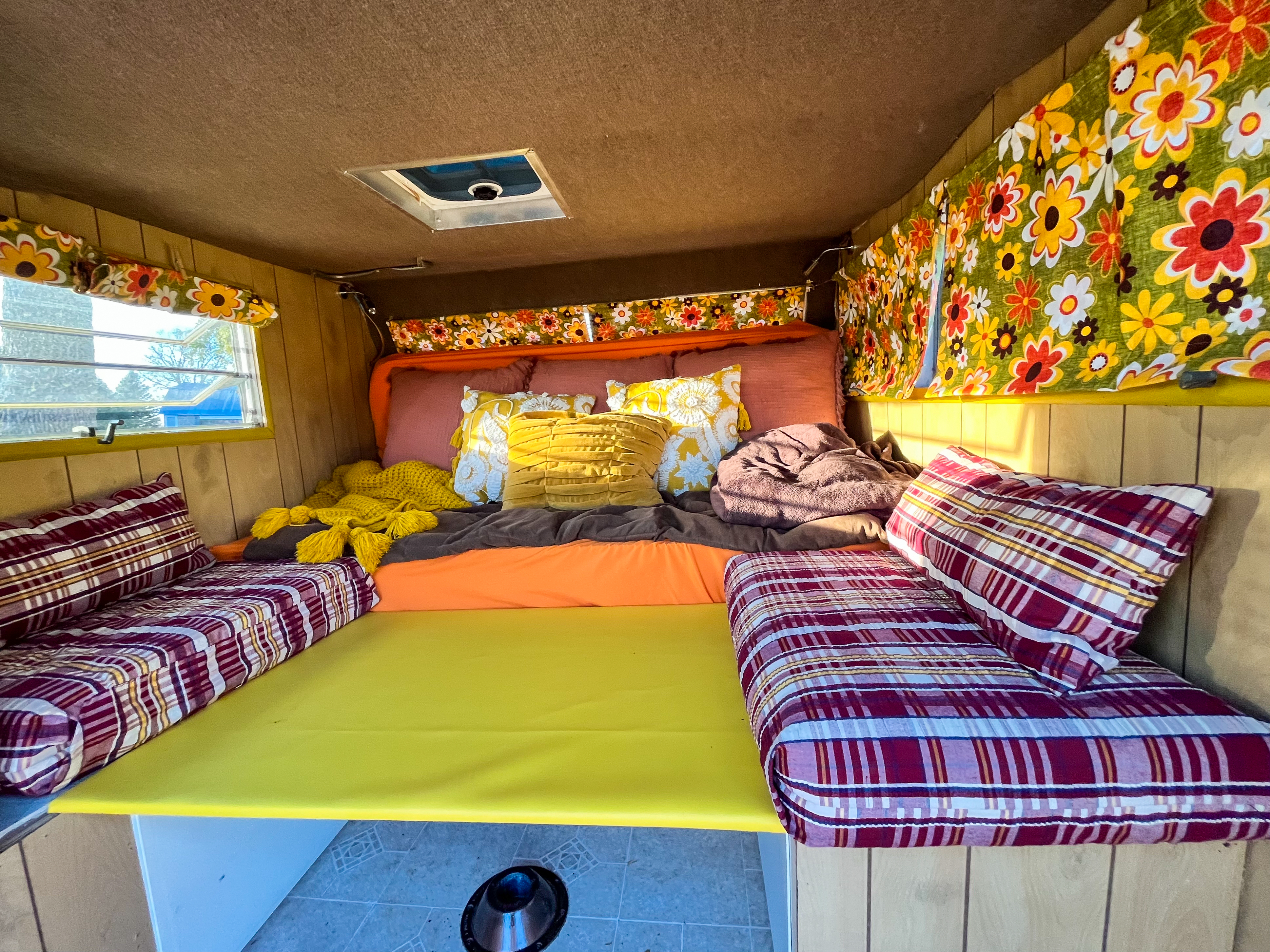 Cozy, colorful, retro RV interior with a bed and floral curtains, ready for your next RV rental adventure.. Custom Camper Trailer 1987