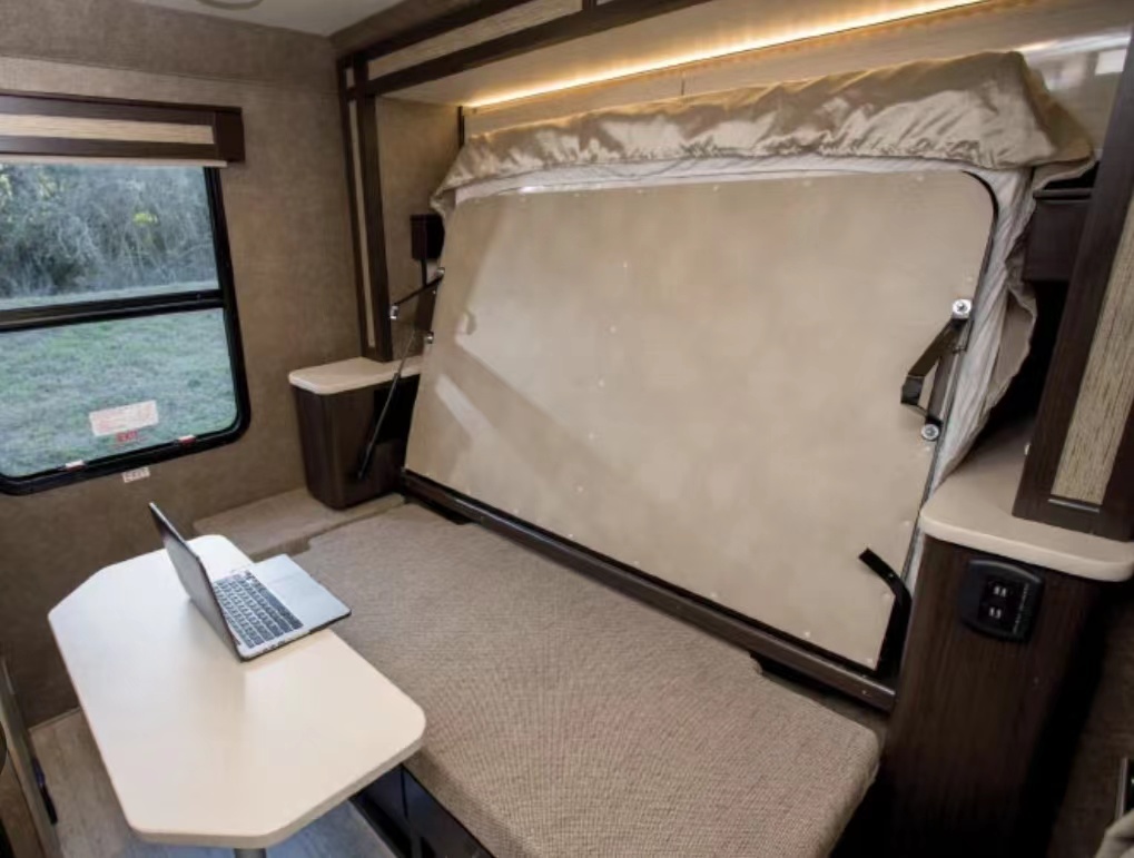 RV rental: Versatile interior with a fold-up bed and a workspace/dining area featuring a laptop.. Thor Compass 2018