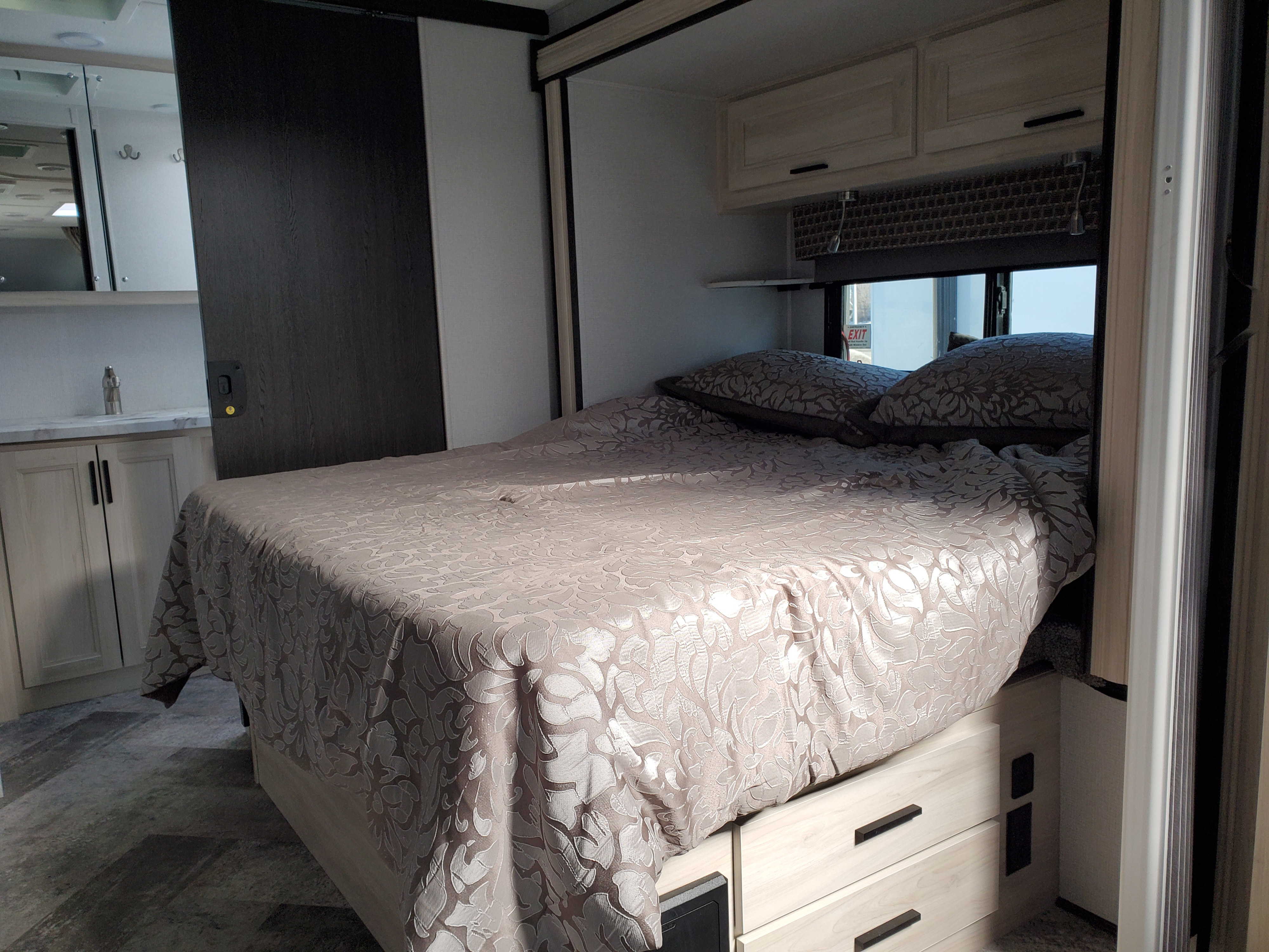 Cozy RV rental bedroom featuring a patterned bedspread, light wood cabinets, and a convenient sliding door.. Forest River Sunseeker 2020