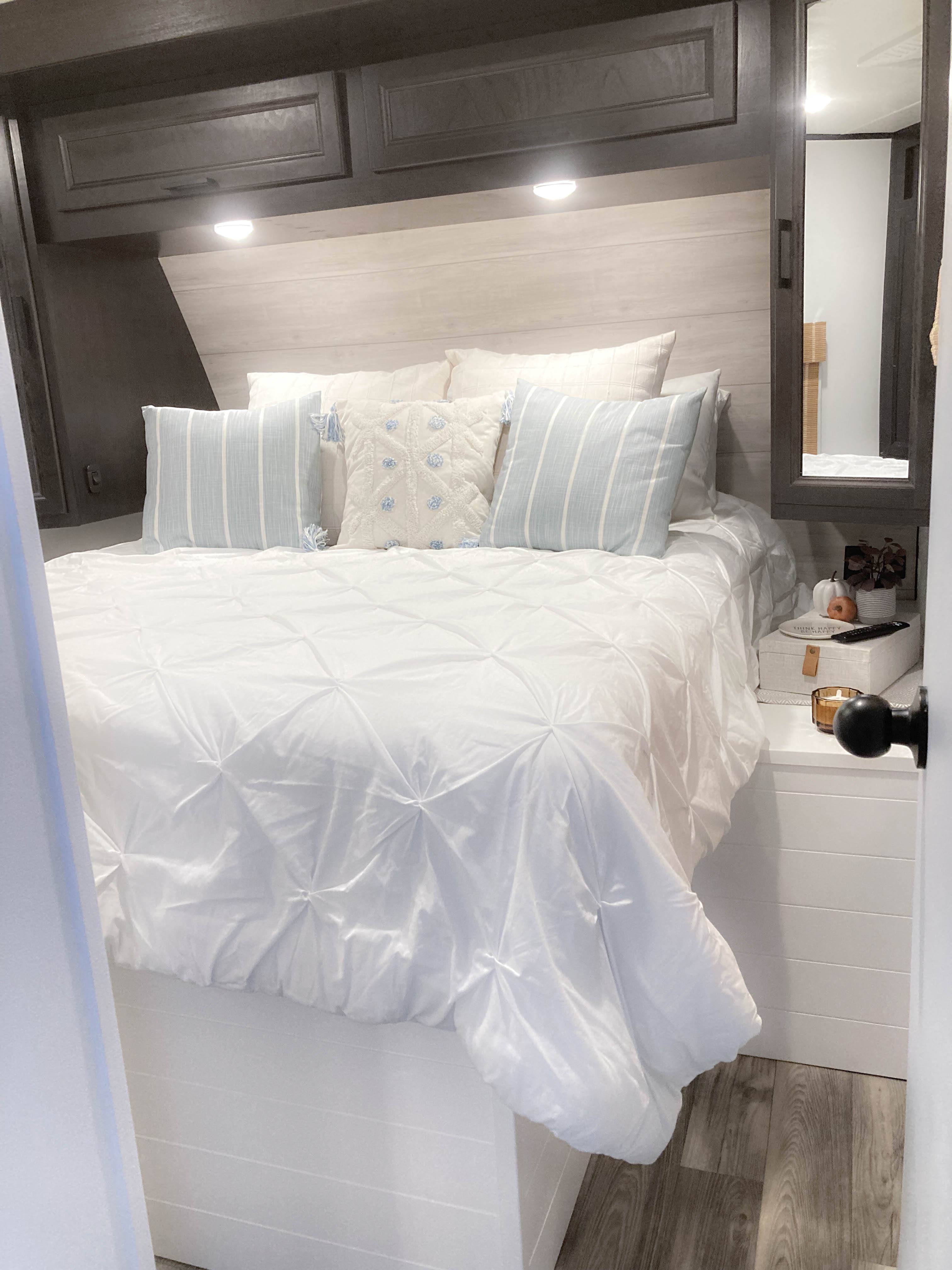 Cozy modern RV rental bedroom with white bedding, blue pillows, and storage. Perfect for comfortable travel.. Jayco Eagle HT 2022