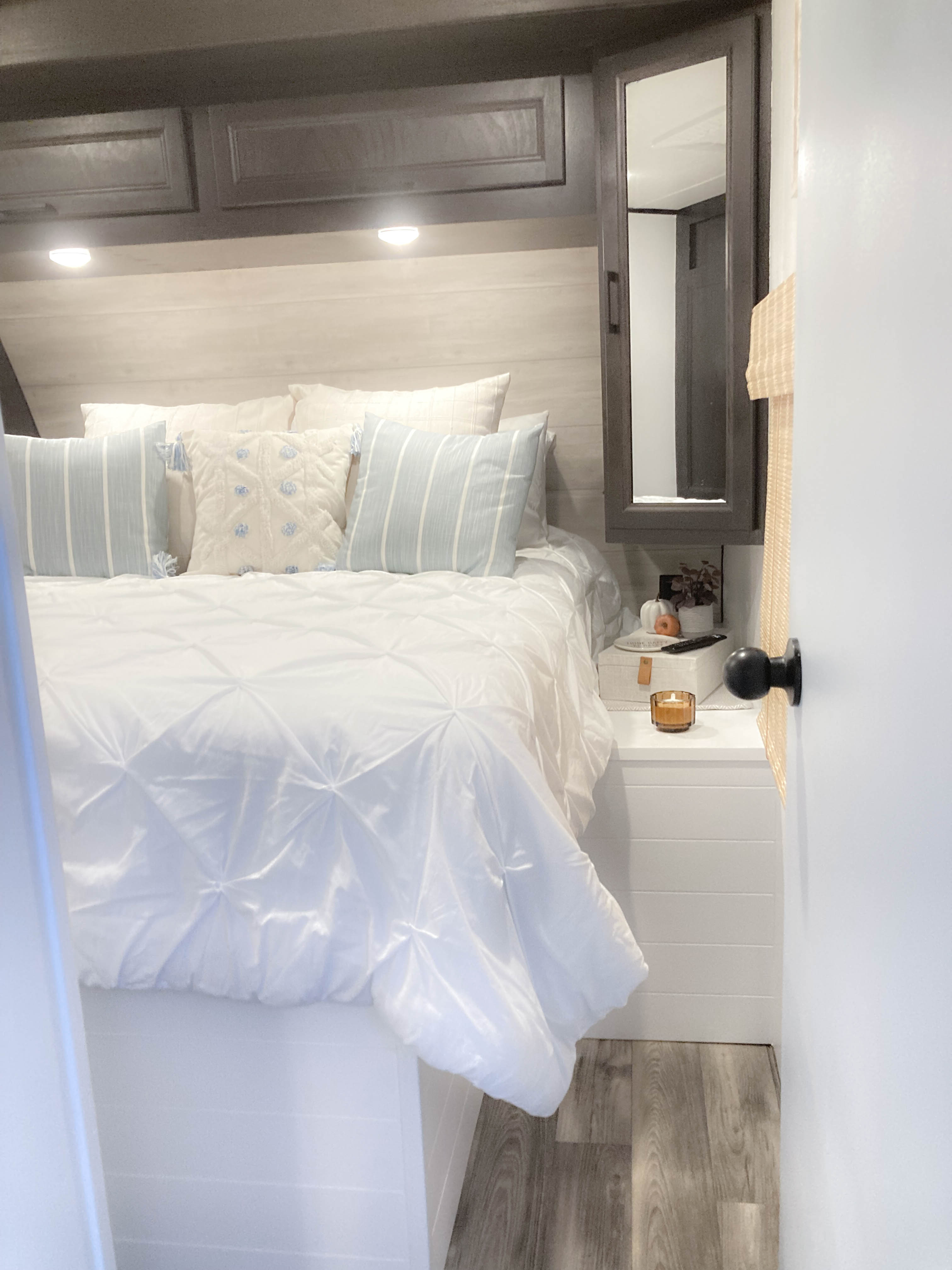 Step into this bright and cozy RV rental bedroom. Features white shiplap walls, a comfy bed with blue/white pillows, and modern overhead storage.. Jayco Eagle HT 2022