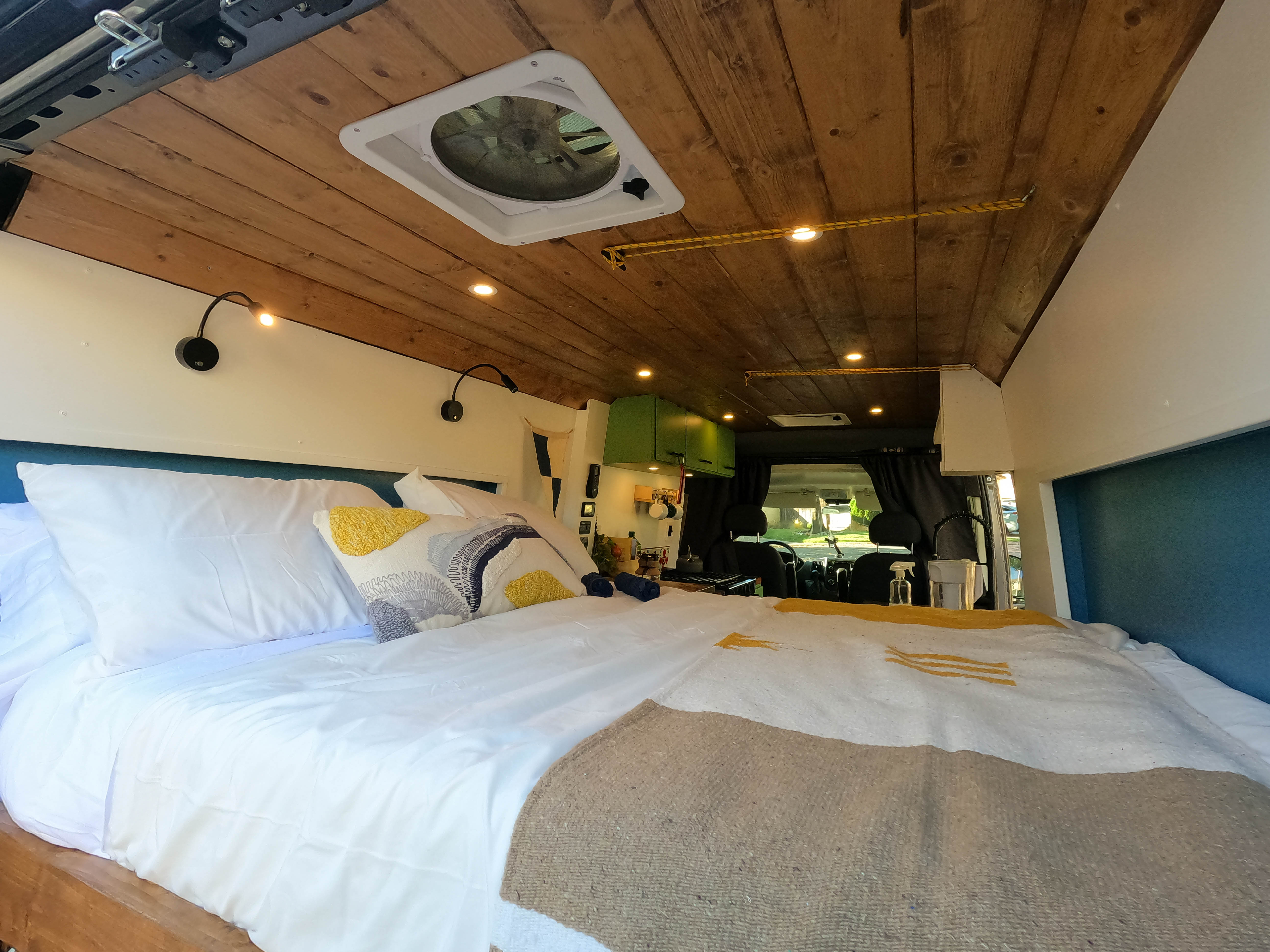Plush bed, wooden ceiling, and bright lighting in this modern RV rental interior. Explore comfort on wheels for your next trip!. Ram Promaster 2500 2021