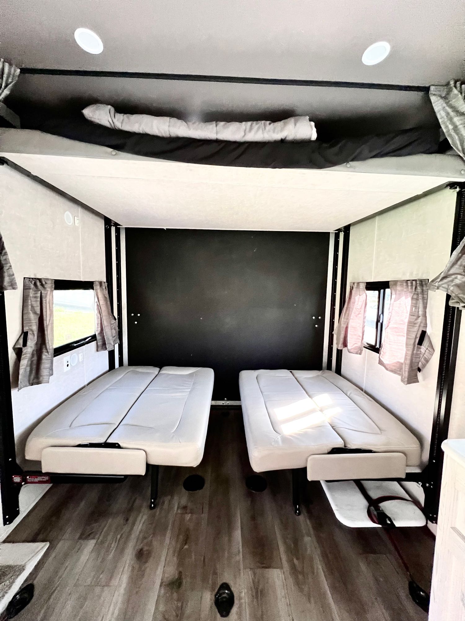Foldable beds and bunk in an RV rental interior, with windows and light wood flooring.. Eclipse Recreational Vehicles Stellar 2023