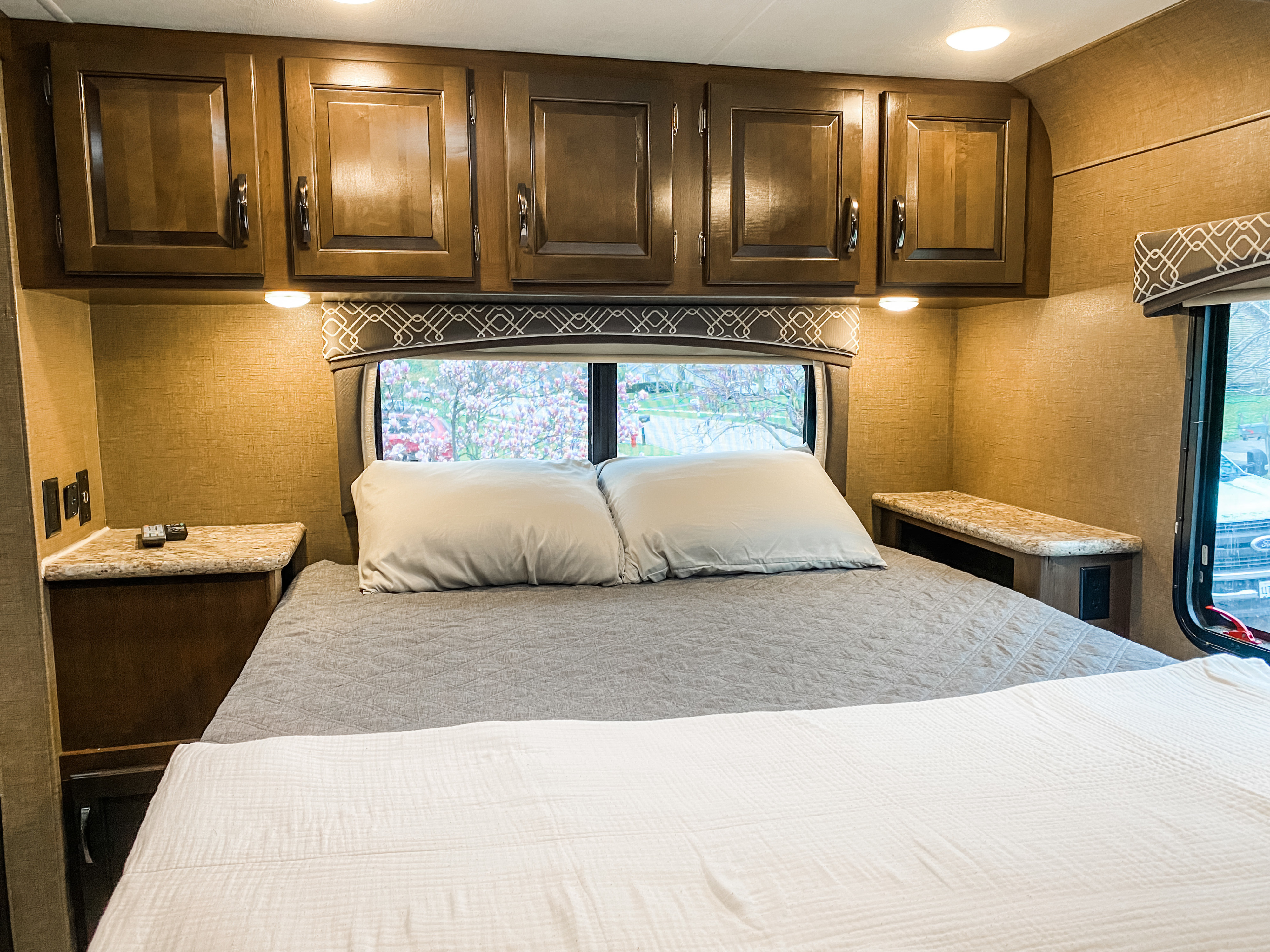 Step into comfort! This RV rental bedroom features a cozy bed, overhead cabinets, and a scenic window view.. Other Chateau 2019