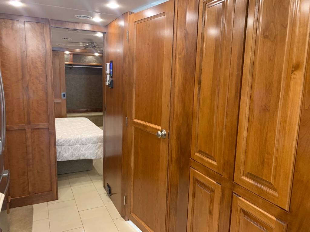 Spacious RV rental interior: view of the bedroom with a bed, and hallway with many handsome wood storage cabinets.. Phaeton Phaeton Motorhome 2015