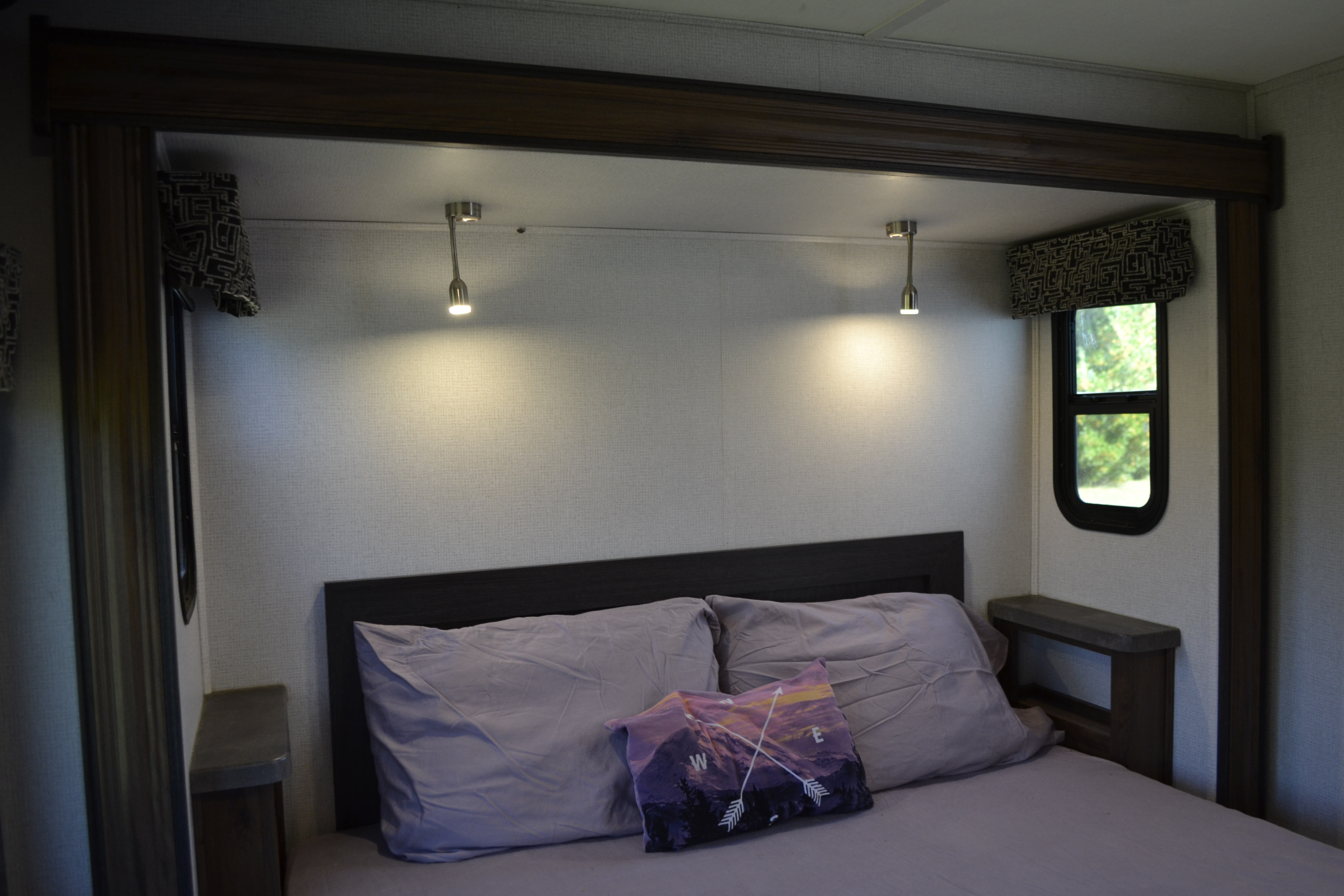 Cozy RV rental bedroom with comfortable bed, reading lights, and windows for a relaxing getaway.. Forest River Sunseeker Classic 2021