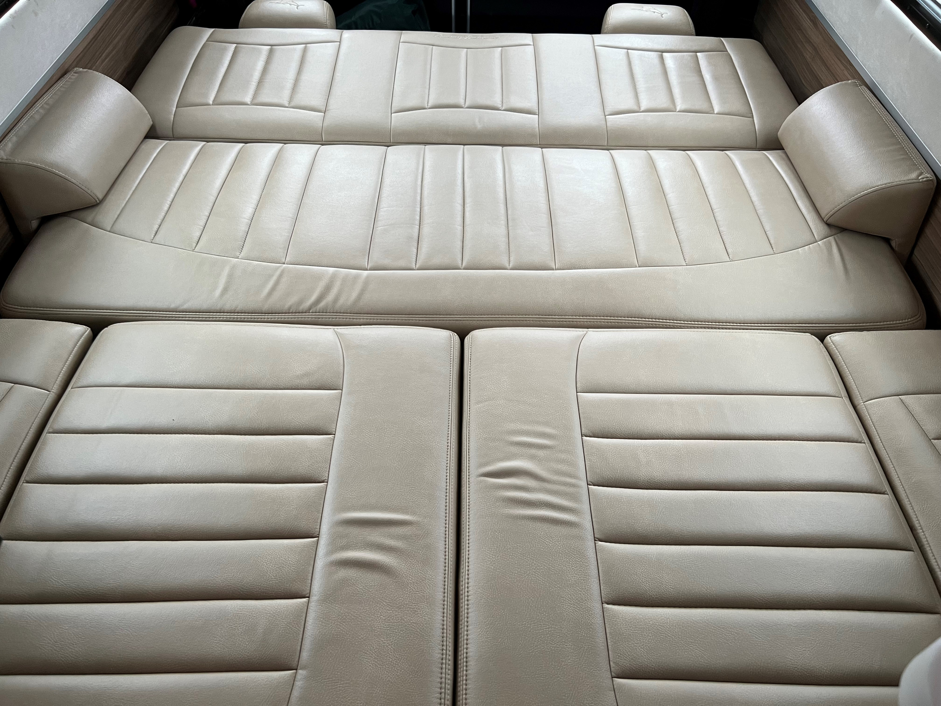 Light beige upholstered seating and bed area in an RV rental, offering comfort and style.. Airstream Interstate 2021