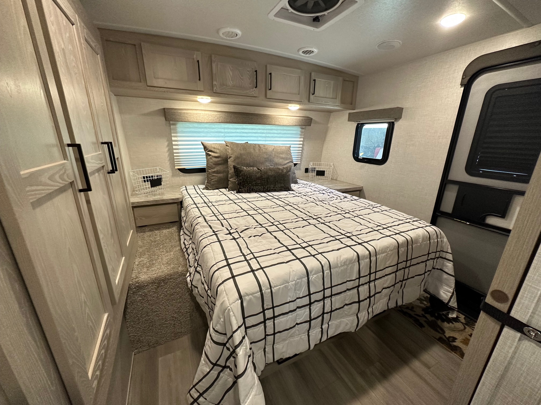 Spacious RV rental bedroom with plaid bedding, overhead cabinets, and built-in closet, offering comfort for your travels.. Forest River Rockwood Ultra Lite 2021