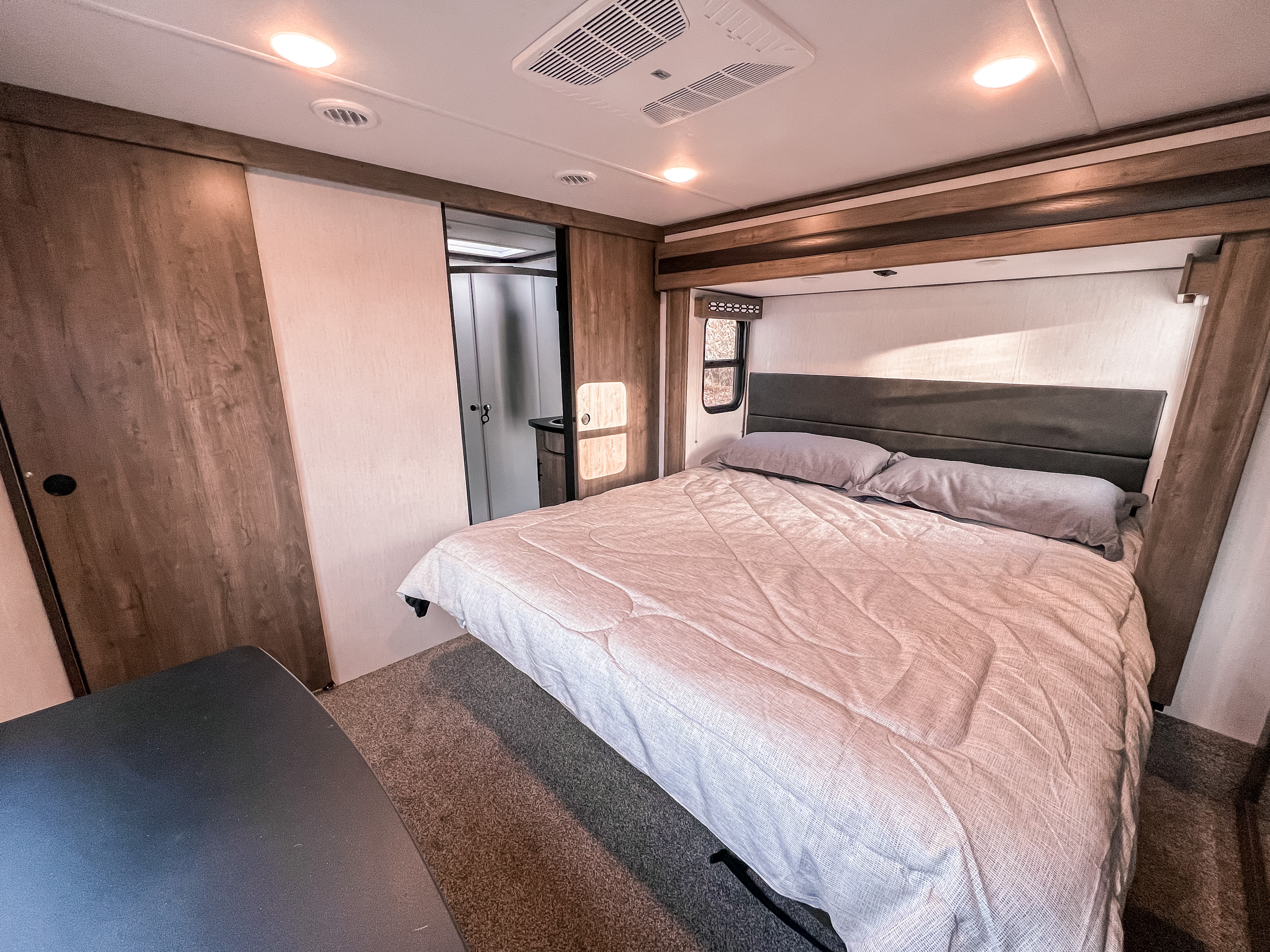 This inviting RV rental bedroom features a comfortable queen bed, modern decor, and easy access to an adjoining bathroom.. Forest River Vengeance 2023