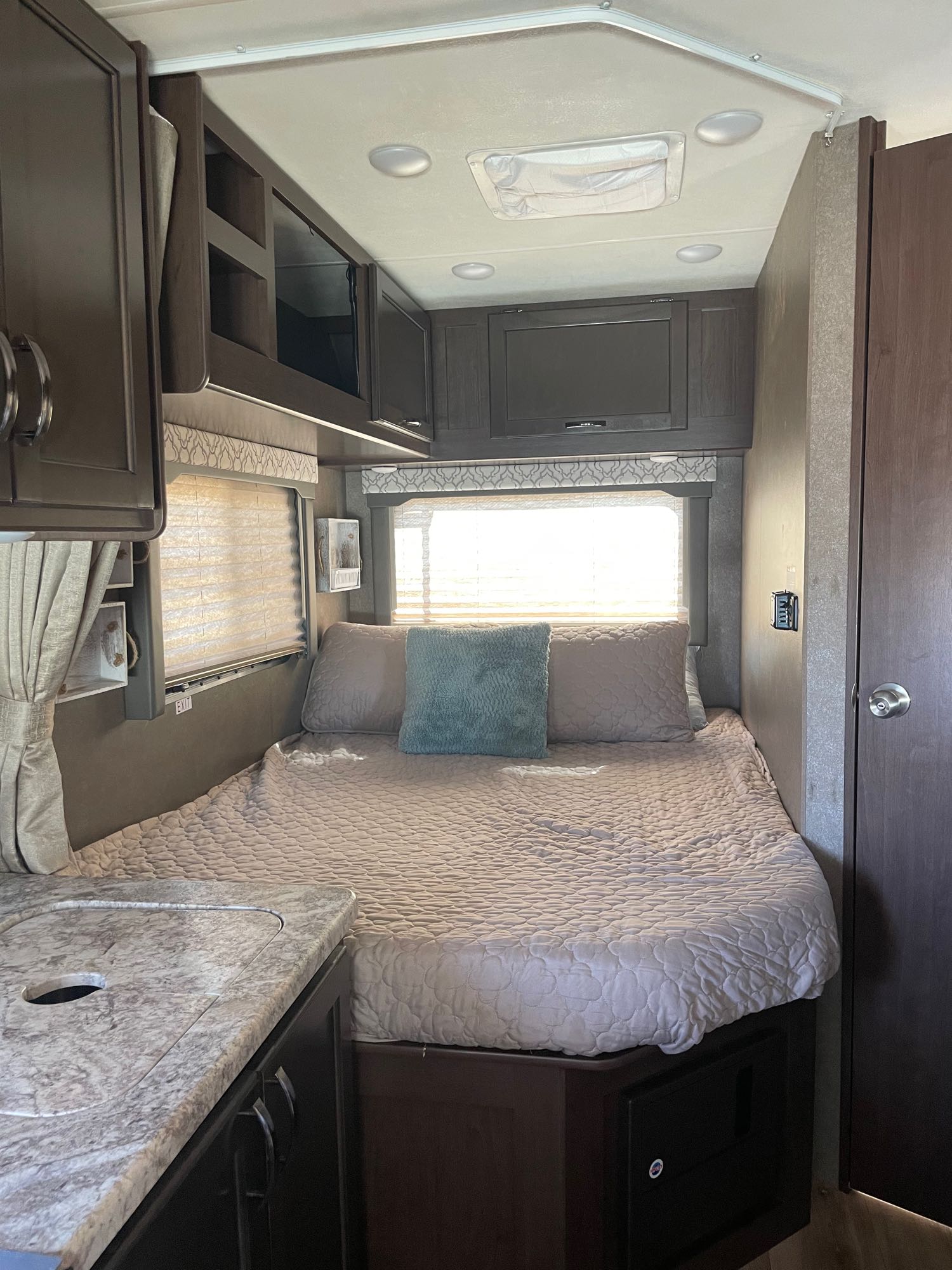 Discover comfort in this RV rental's cozy bedroom, featuring a bed, window, and overhead storage.. Thor Freedom Elite 2020