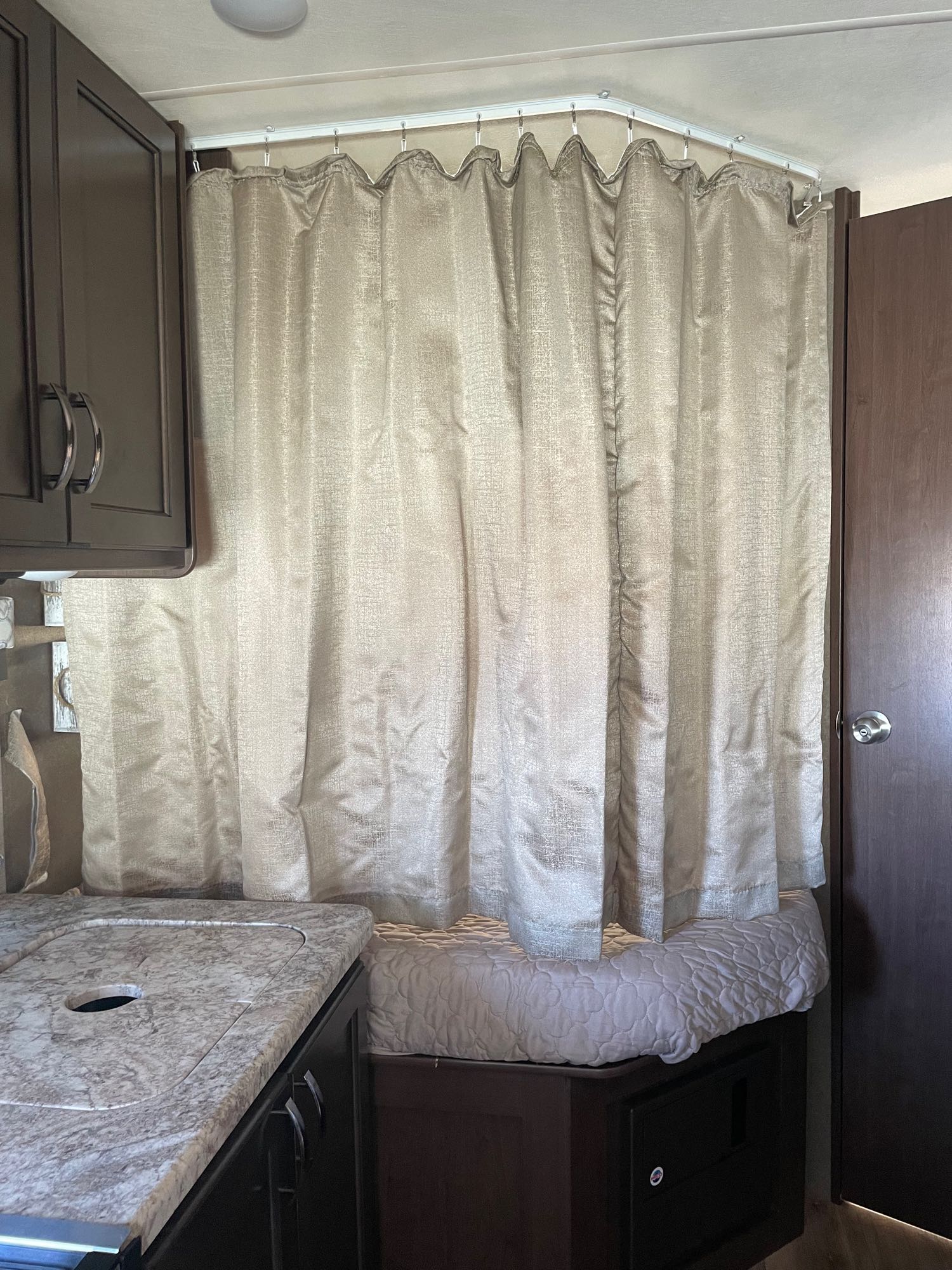 An RV rental interior featuring a beige privacy curtain on a curved track, kitchen counter, and bed.. Thor Freedom Elite 2020