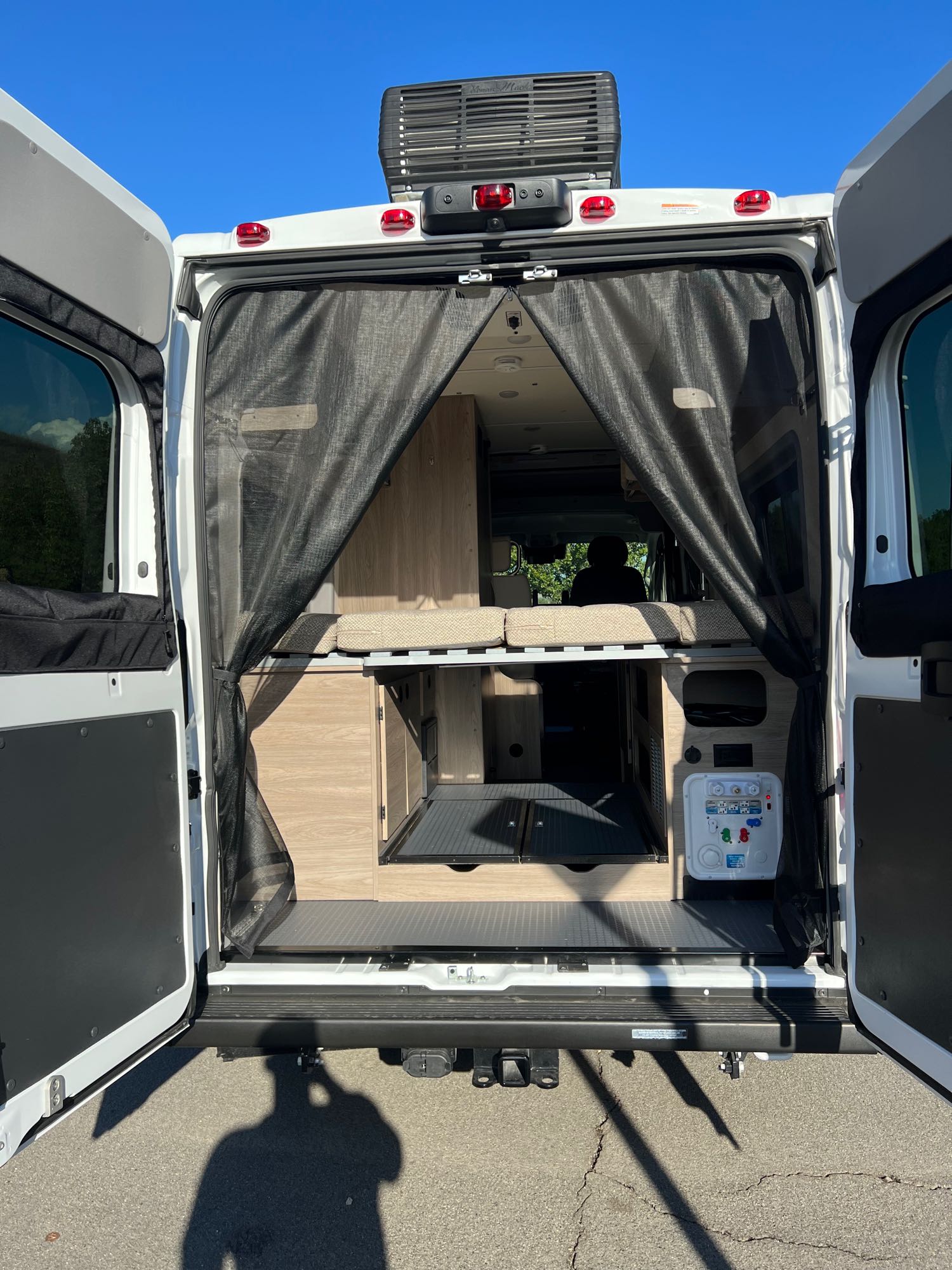 Explore this RV rental camper van's spacious interior! Rear doors open to reveal versatile beds, storage, and a utility panel.. Winnebago Solis 2023
