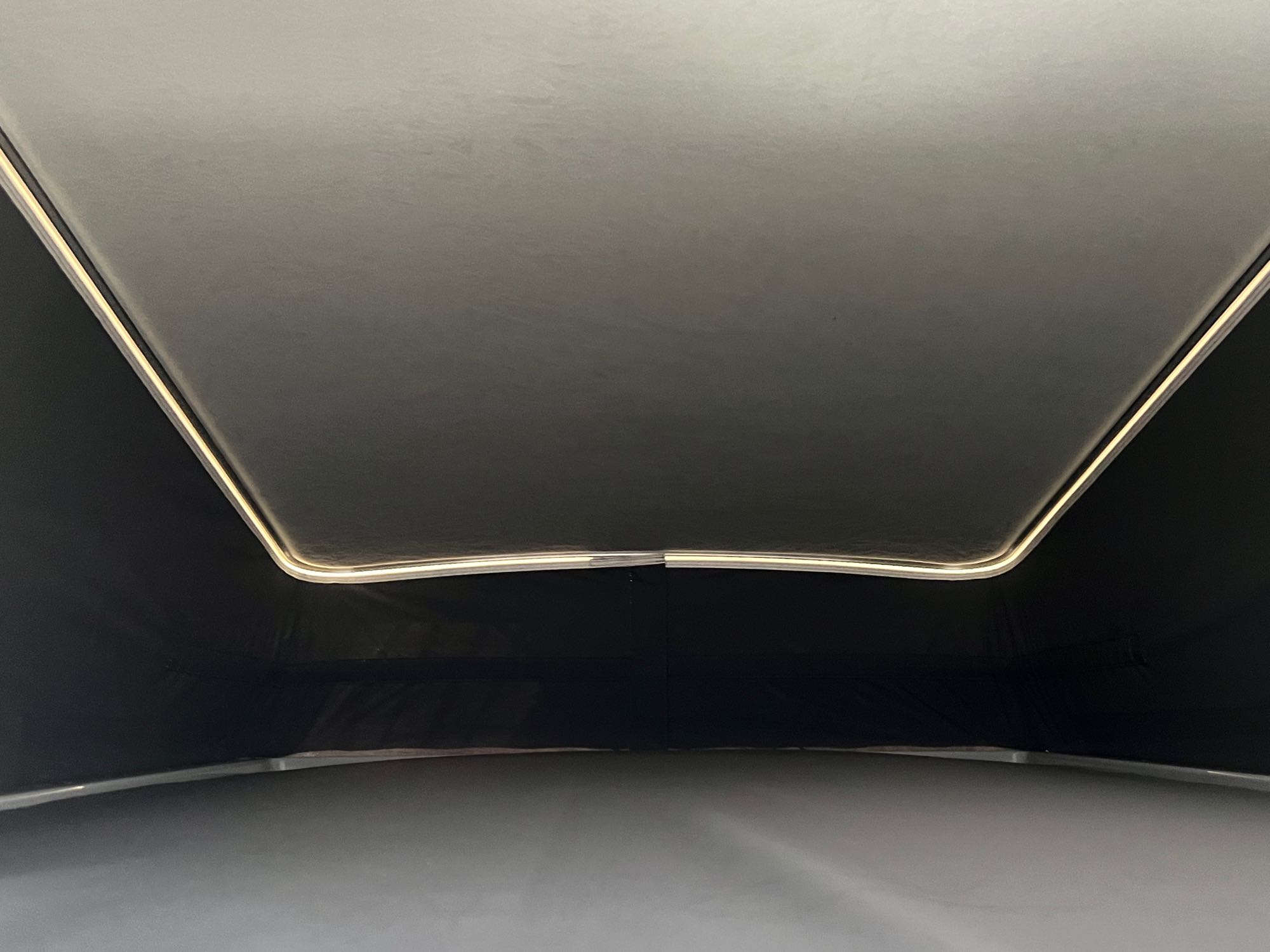 Inside an RV rental: A modern interior view looking up at the light gray ceiling and dark walls, outlined by warm LED lighting.. Winnebago Solis 2023