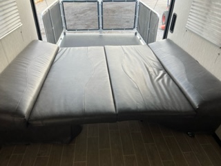 This RV rental's toy hauler interior features a large sofa bed and a rear ramp door with patio screen system.. Forest River Grey Wolf 27RR 2020