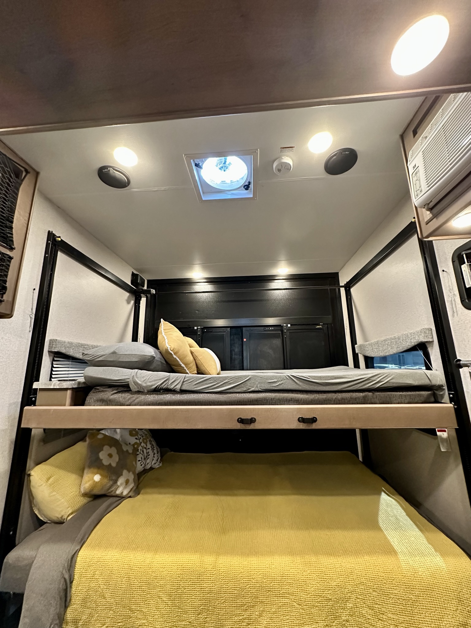 Inside an rv rental: dual bunk beds with comfy linens, overhead lights, and an AC unit for a great night's sleep.. Thor Motor Coach Outlaw 2023