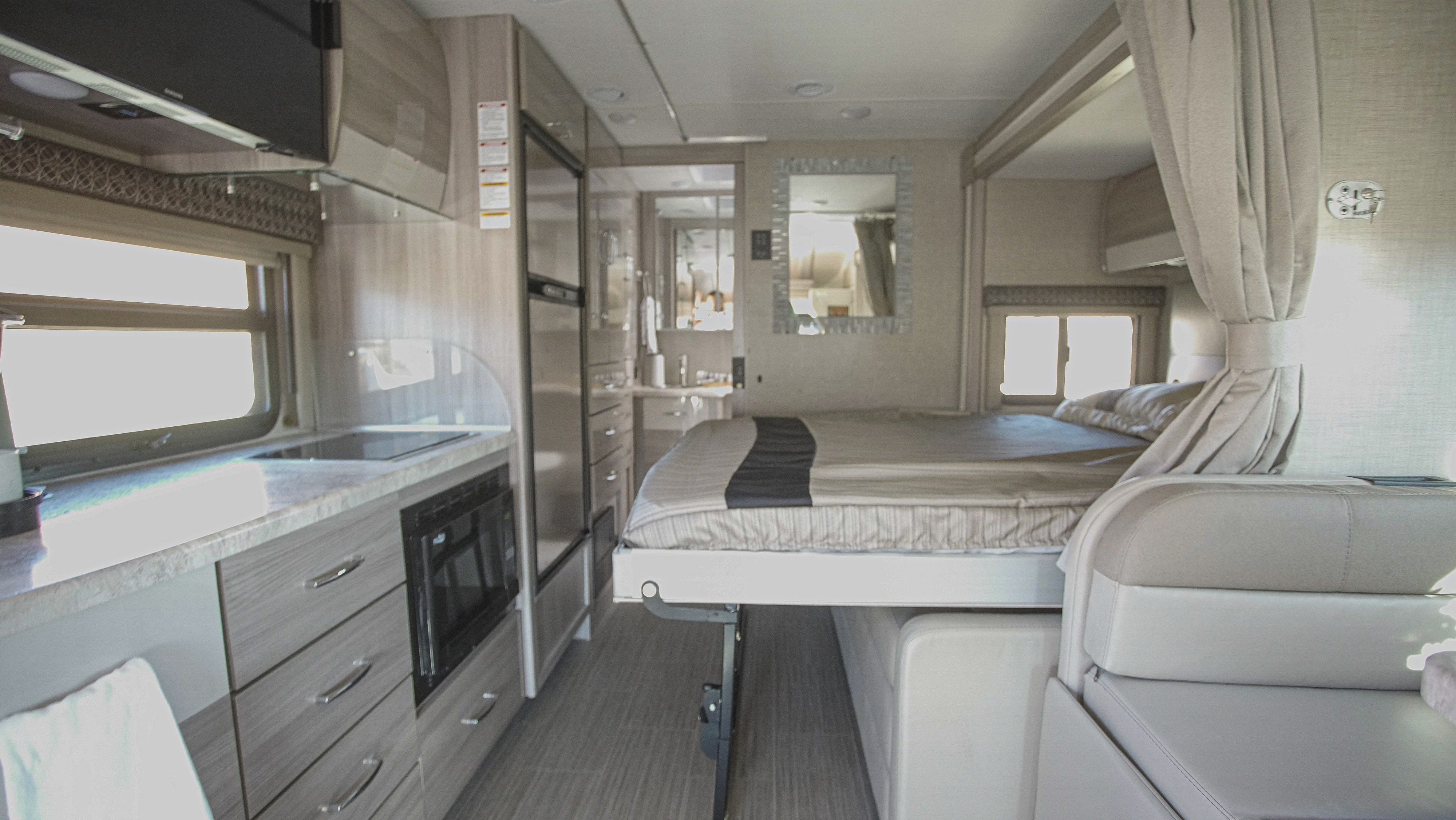 RV rental interior: Bright, modern kitchen with microwave, elevated bed over a dinette, and comfortable living space.. Thor Motor Coach Tiburon 24FB 2023