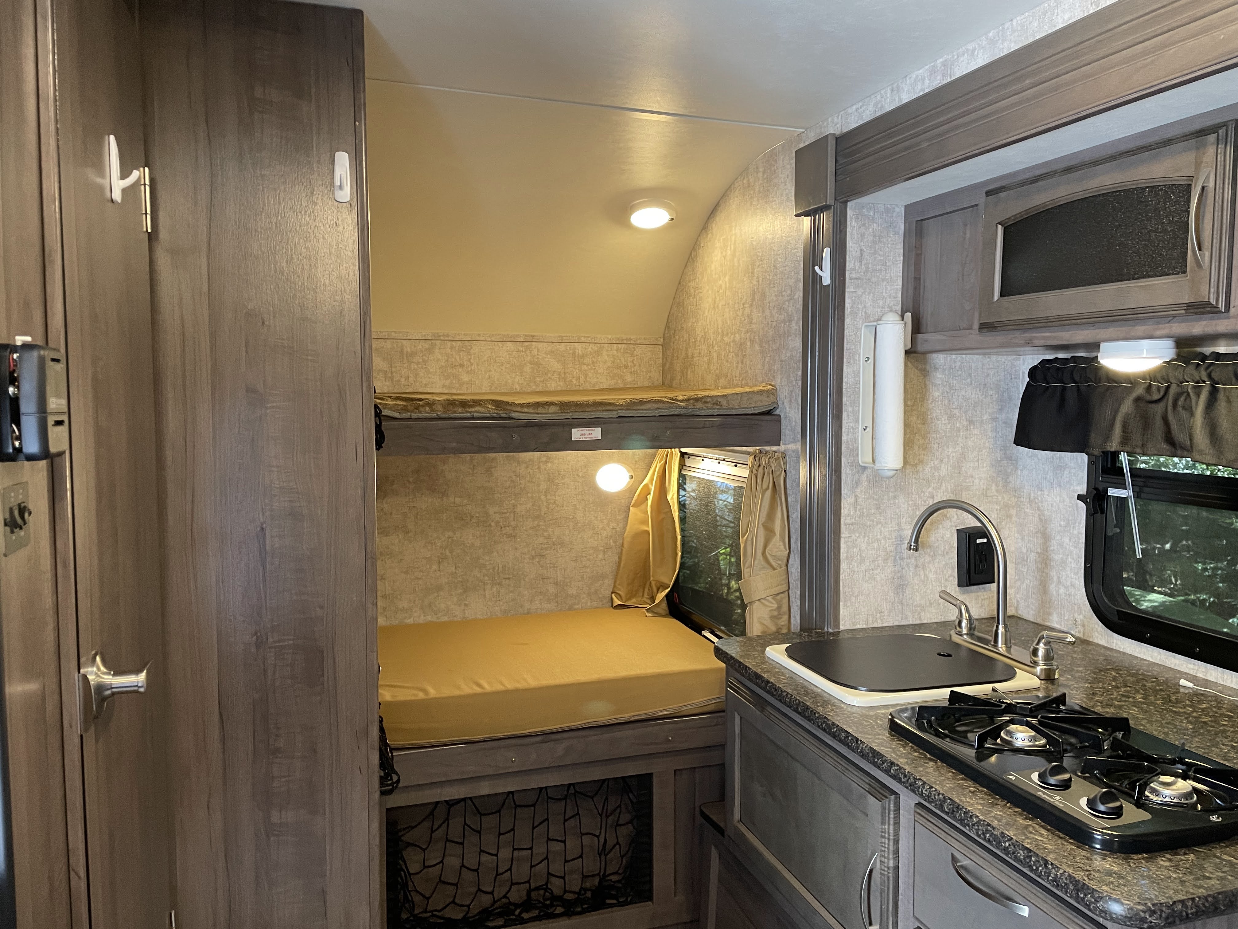 Inside an RV rental: functional kitchen with sink & stove, plus comfortable bunk beds, perfect for family trips.. Winnebago Winnie Drop 170k 2017