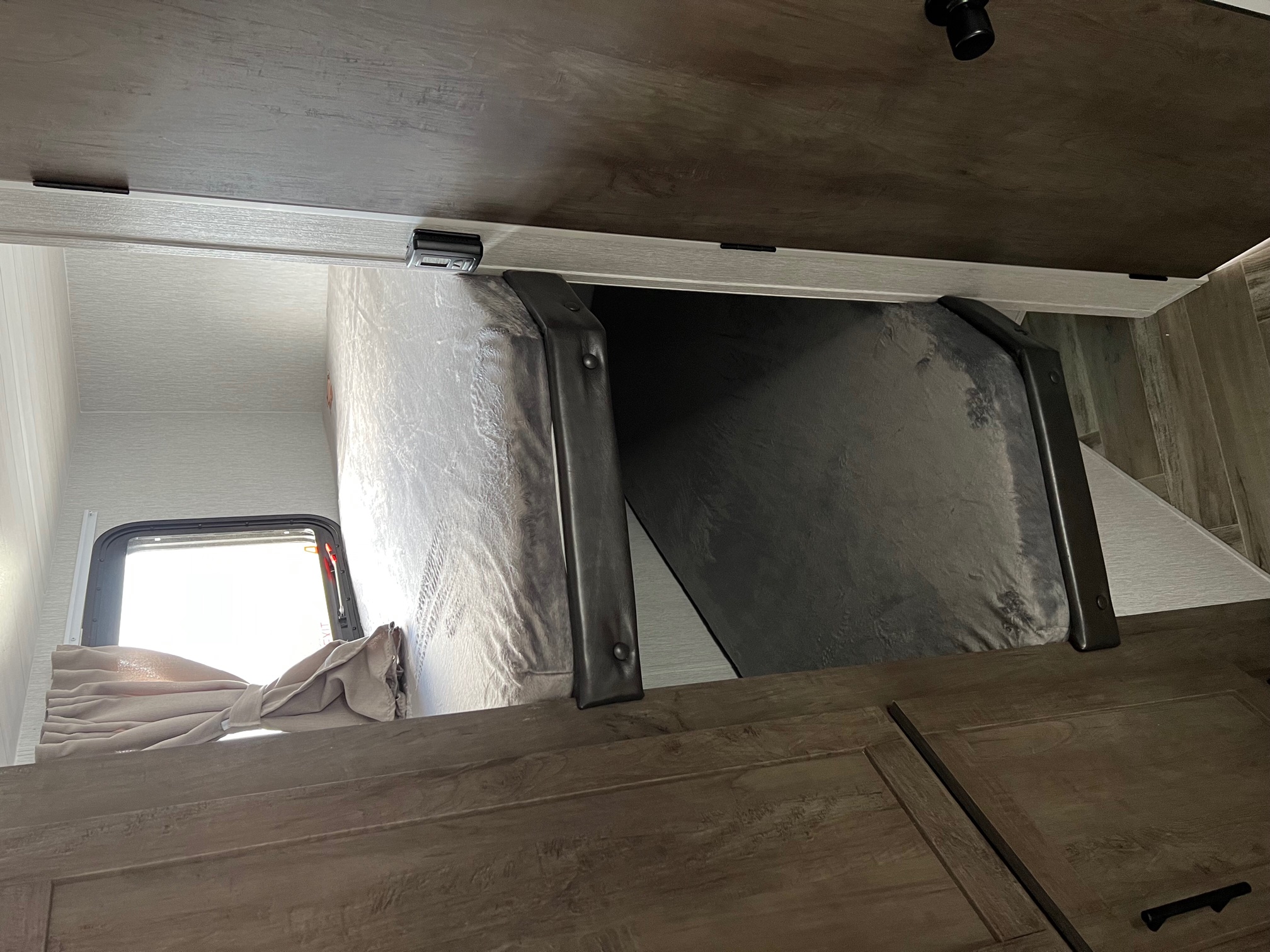 RV rental interior: stacked bunk beds with light from a window, offering cozy sleeping space for your mobile adventures.. Forest River Wildwood X-Lite 2023