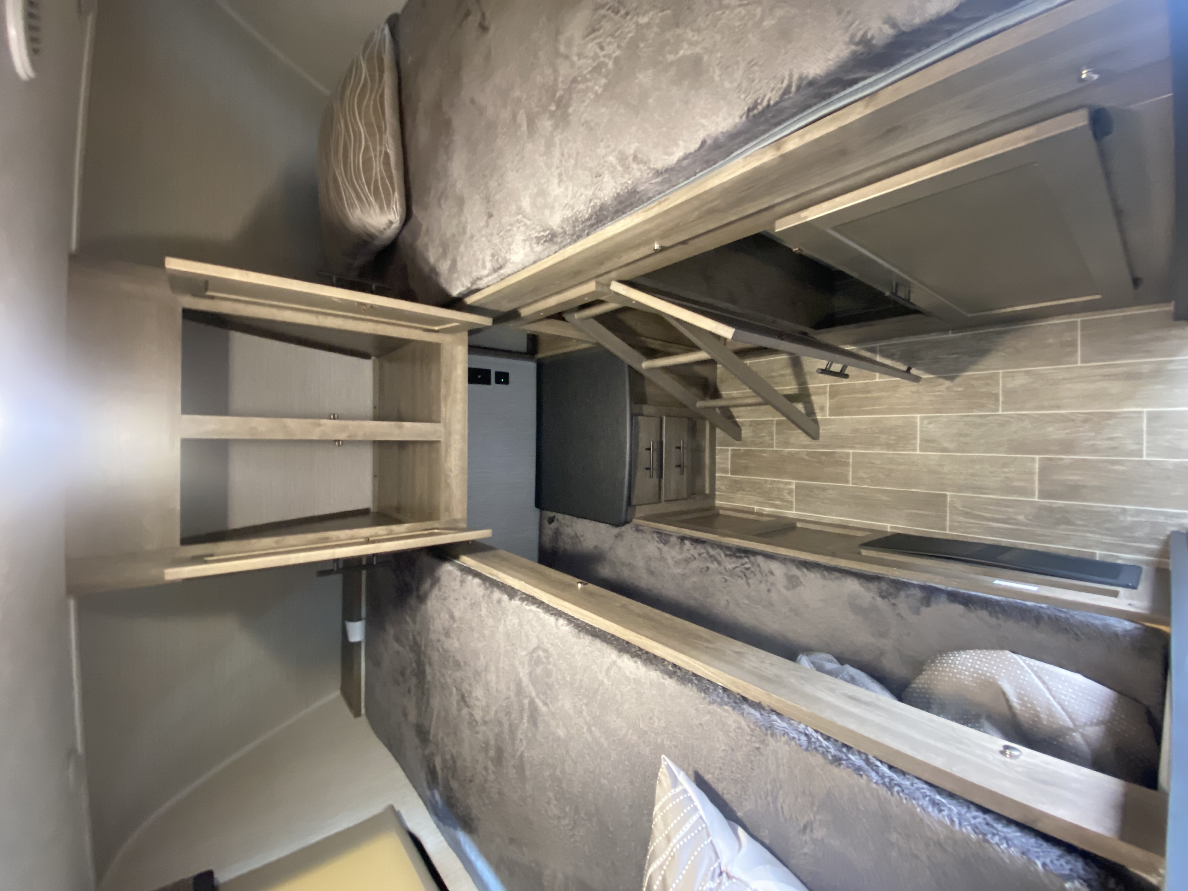 This RV rental bedroom features a cozy bed with overhead storage shelves and a retractable TV mount for compact living.. Forest River Palomino Puma 2020