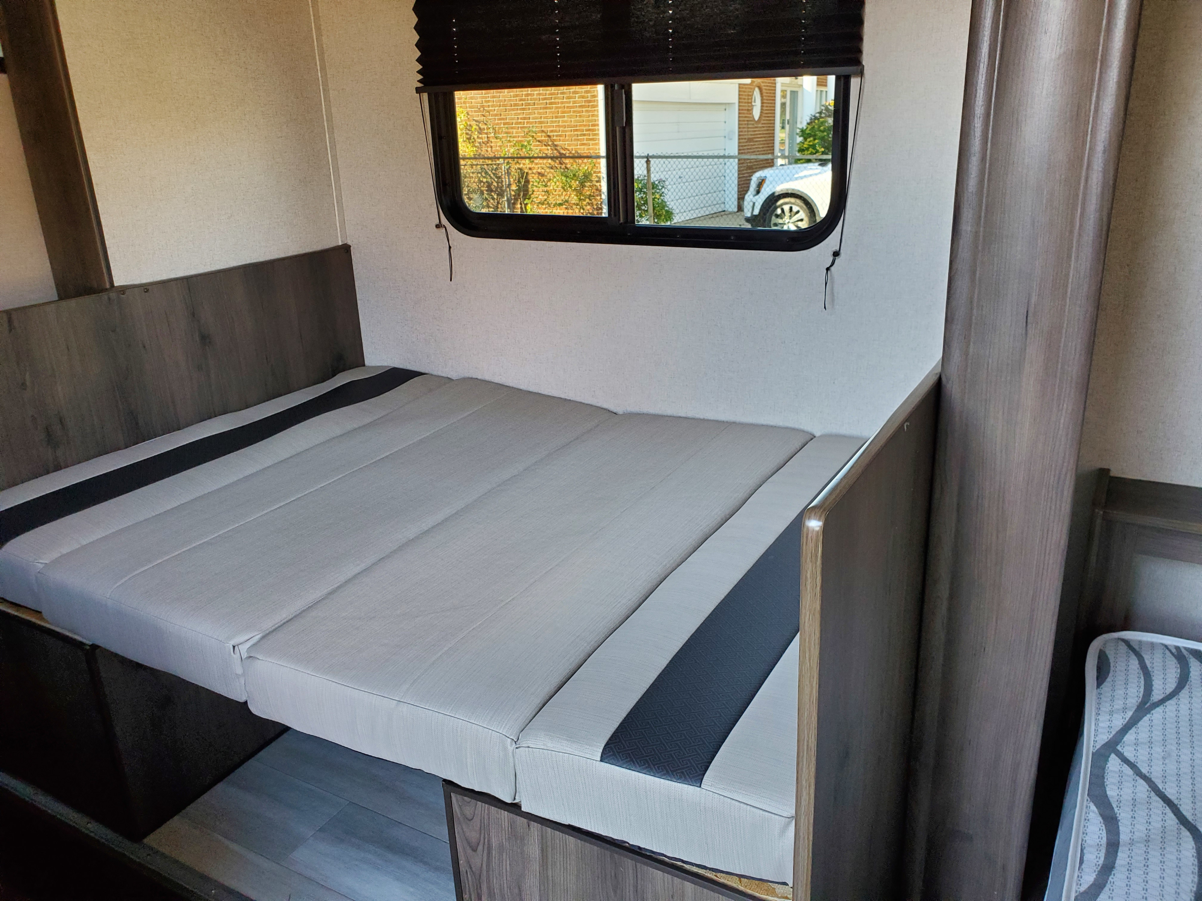Cozy RV rental interior featuring a versatile bed/dinette area with light-grey cushions, dark wood accents, and a window.. Clipper Clipper Trailer 2021