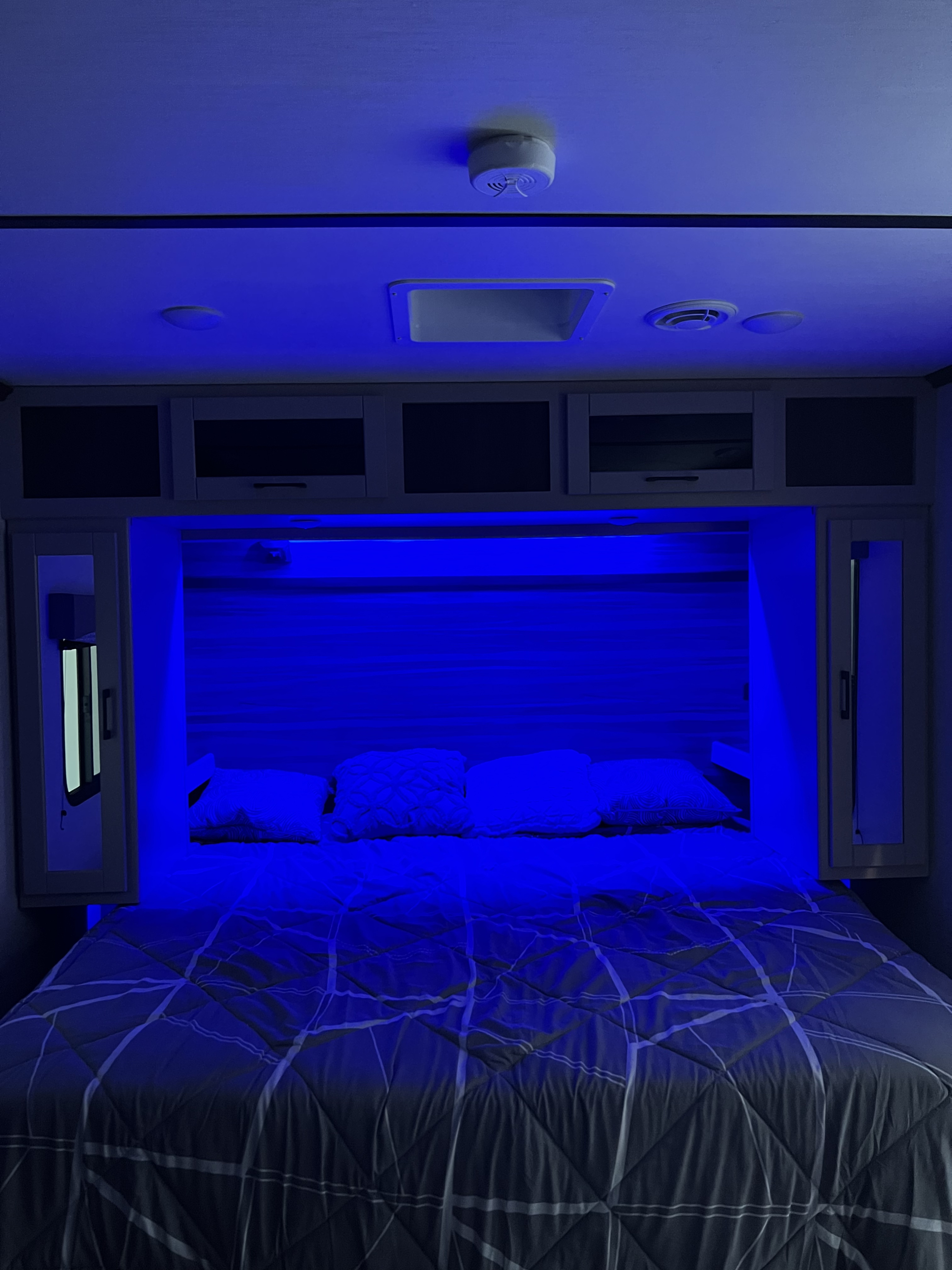 Cozy RV rental bedroom with modern blue accent lighting, a comfortable bed, and overhead storage.. Crossroads RV Cruiser Aire 2022