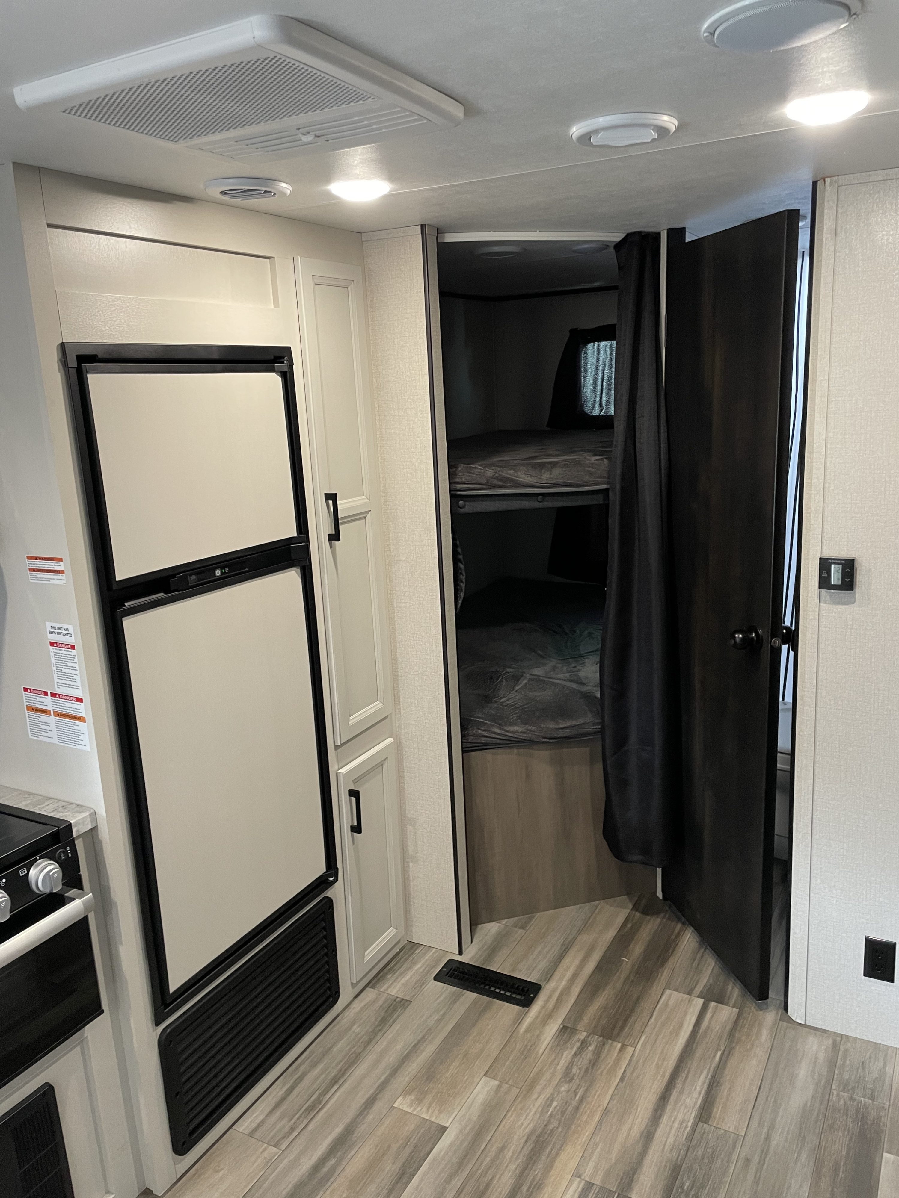 RV rental interior: A compact kitchen with a fridge, integrated bunk beds, and functional design for comfortable travel.. Open range 26bhs 2022