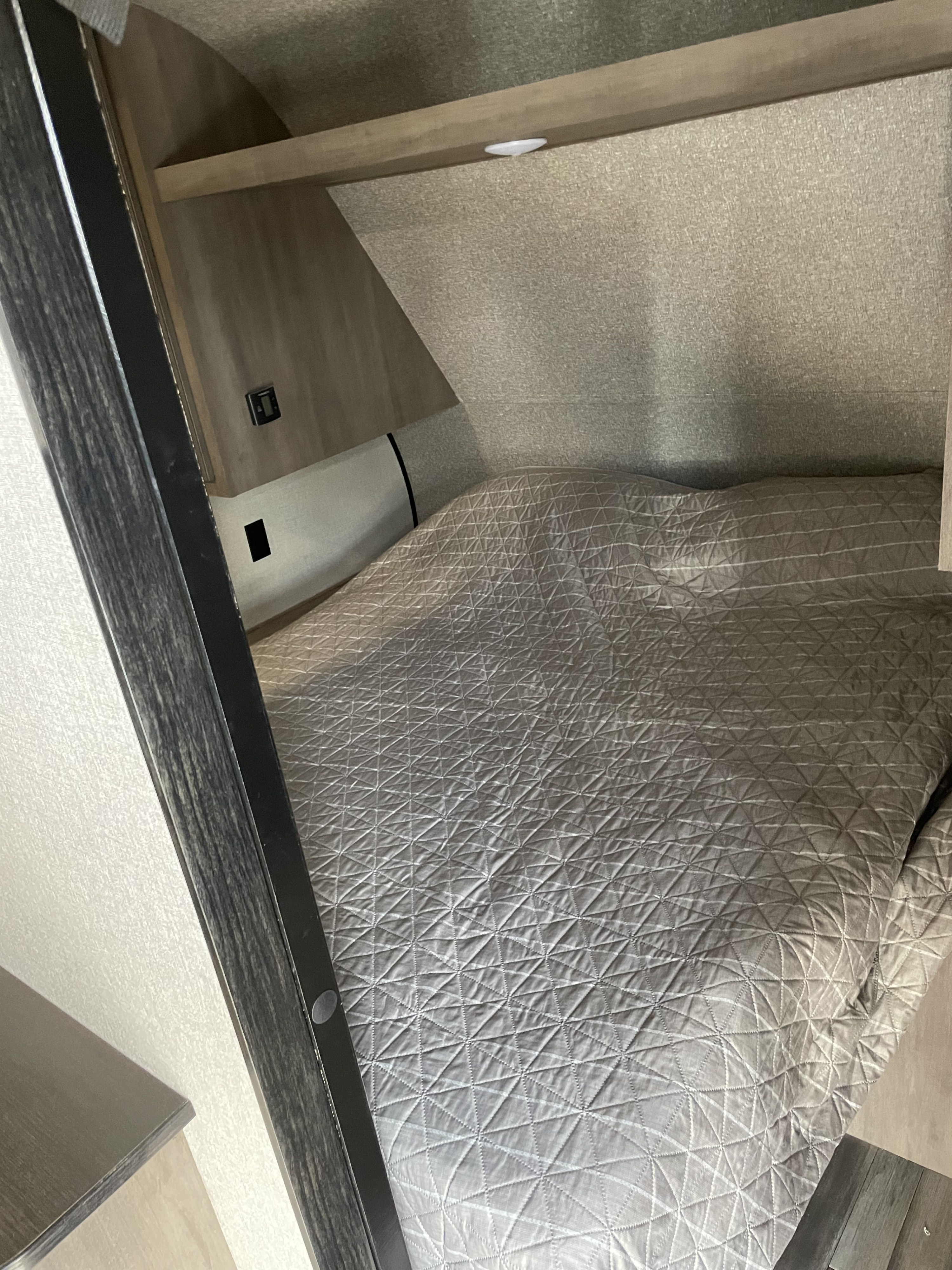 Cozy RV rental bed with quilted cover and sleek interior design. Ideal for a comfortable stay on the road.. Open range 26bhs 2022