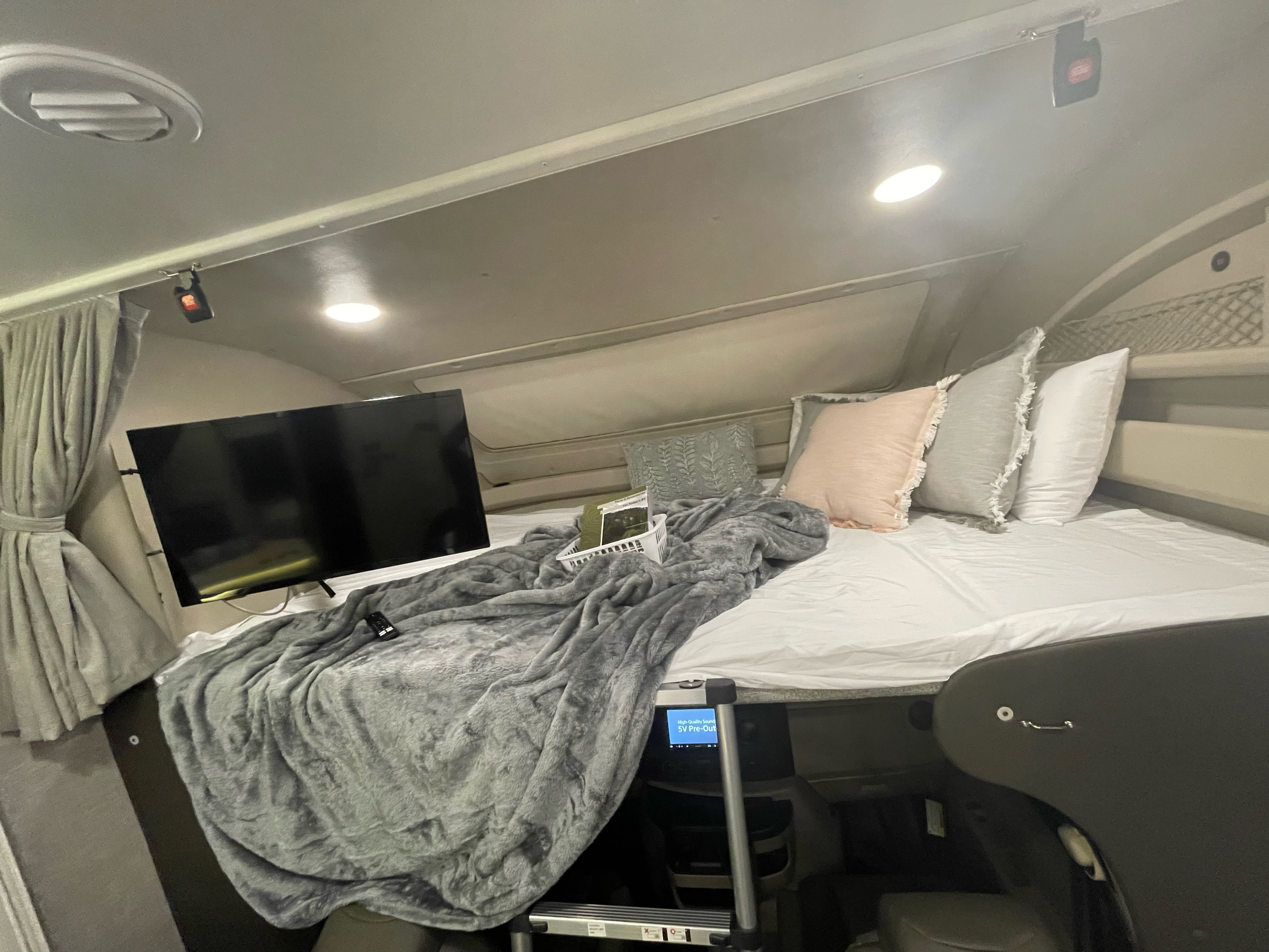 Cozy RV rental bedroom features a comfy bed with soft blankets, pillows, and a TV, ideal for comfortable travel.. Entegra Coach Odyssey 2023