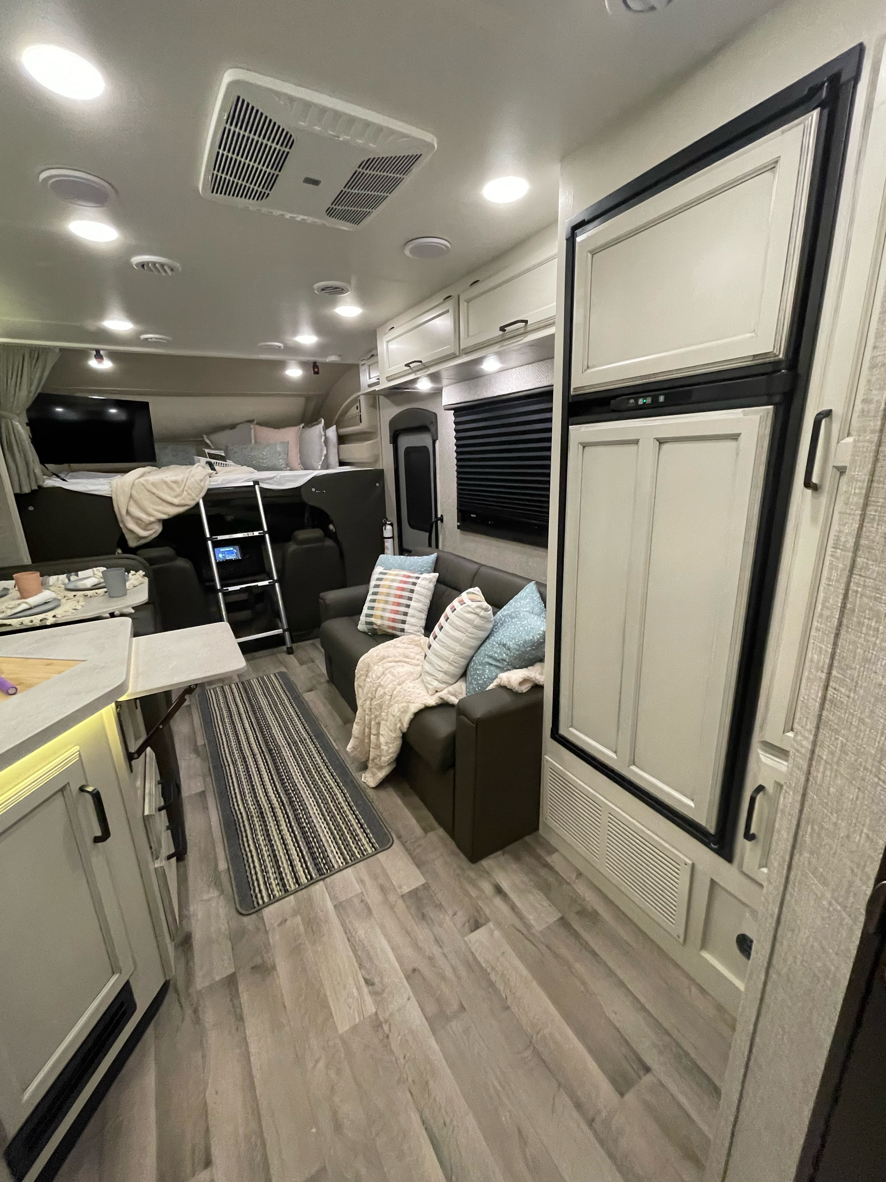 Inside a spacious RV rental: a comfortable living area, kitchen, and unique bunk with TV for family trips.. Entegra Coach Odyssey 2023