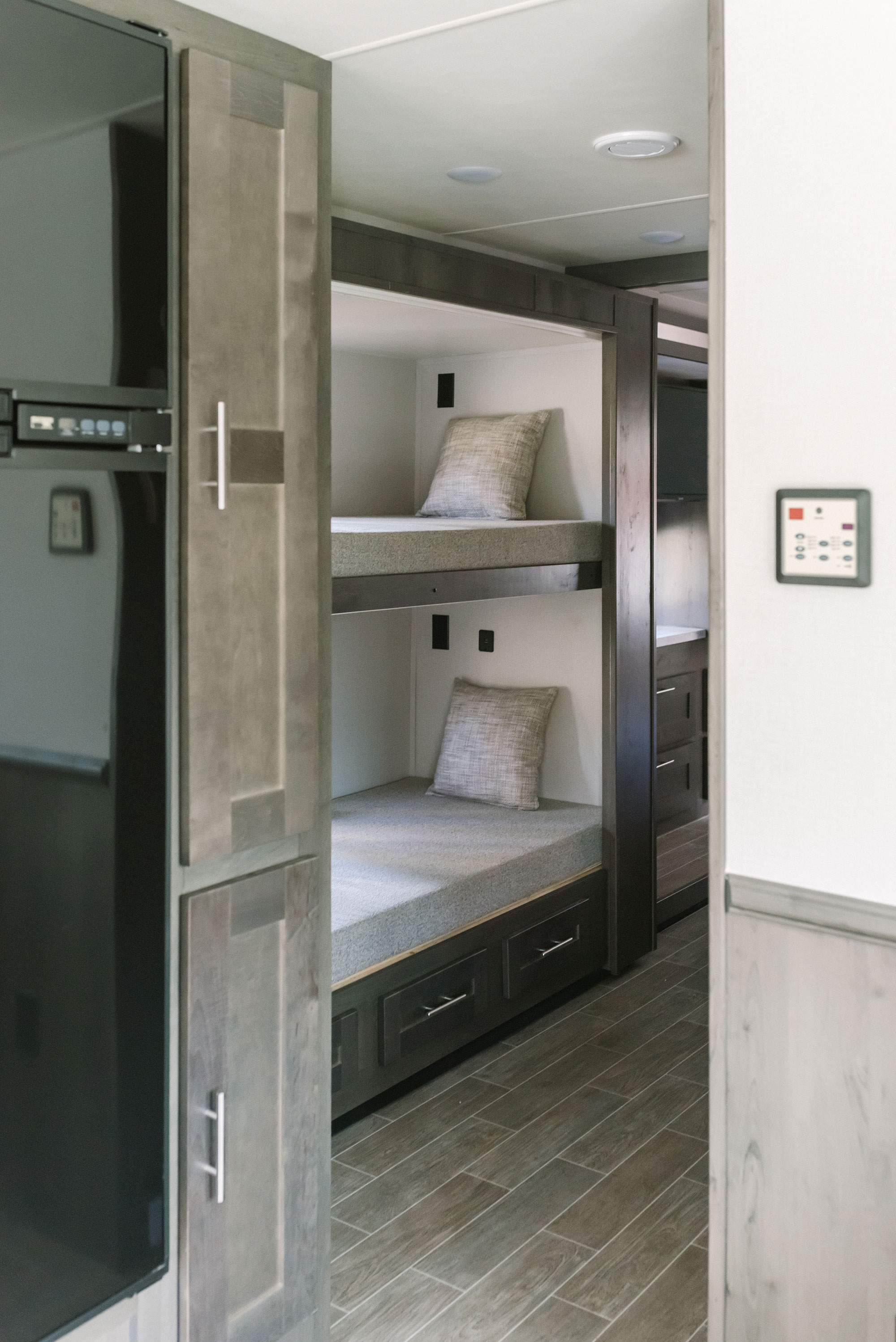 Modern RV rental interior with cozy bunk beds, a refrigerator, and control panel, featuring wood-look flooring.. Forest River Georgetown 2021