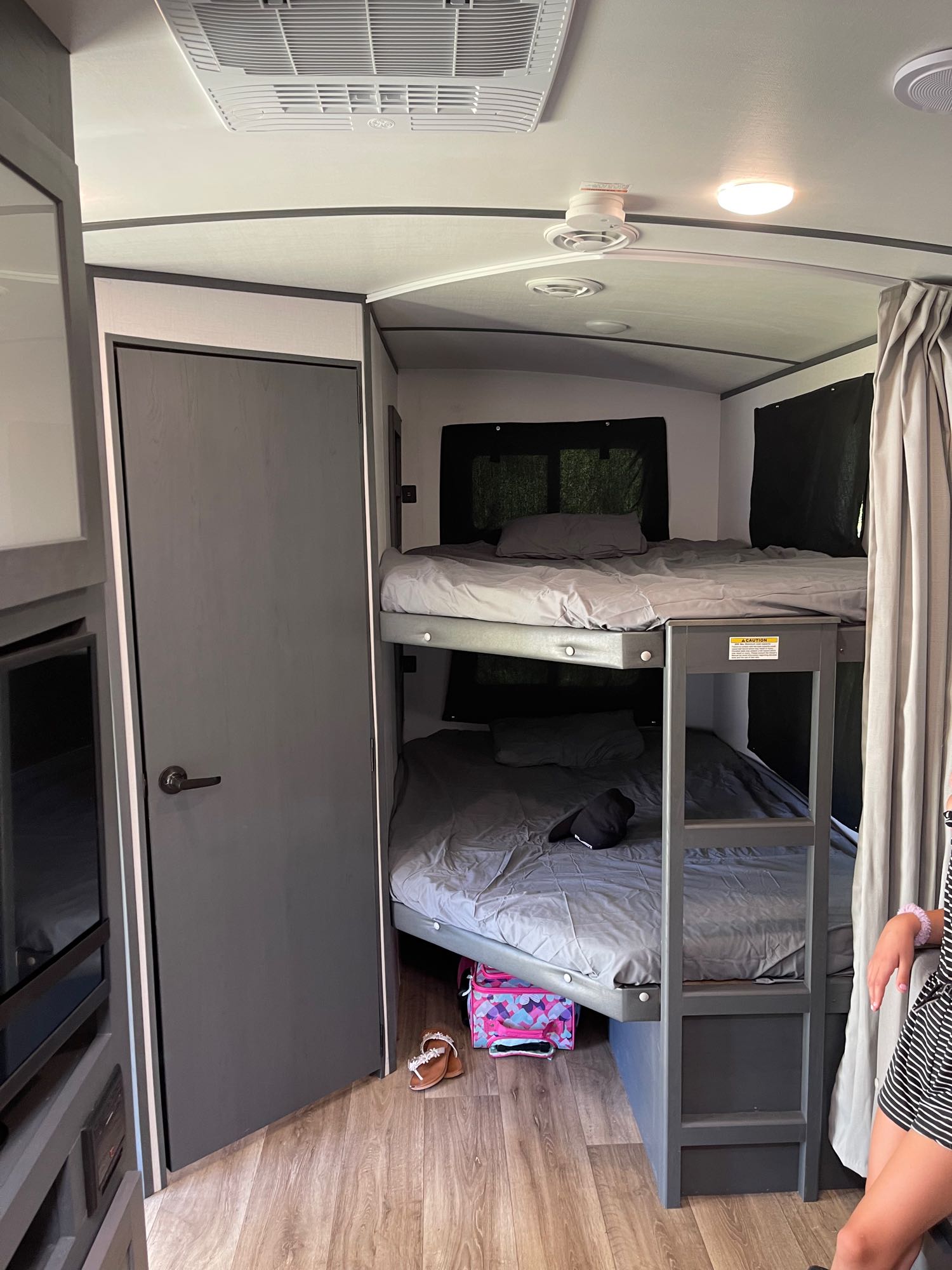 RV rental interior: view of bunk beds, door, and ceiling AC. Cozy, compact sleeping area in a travel trailer.. Keystone Bullet 250BHS 2022