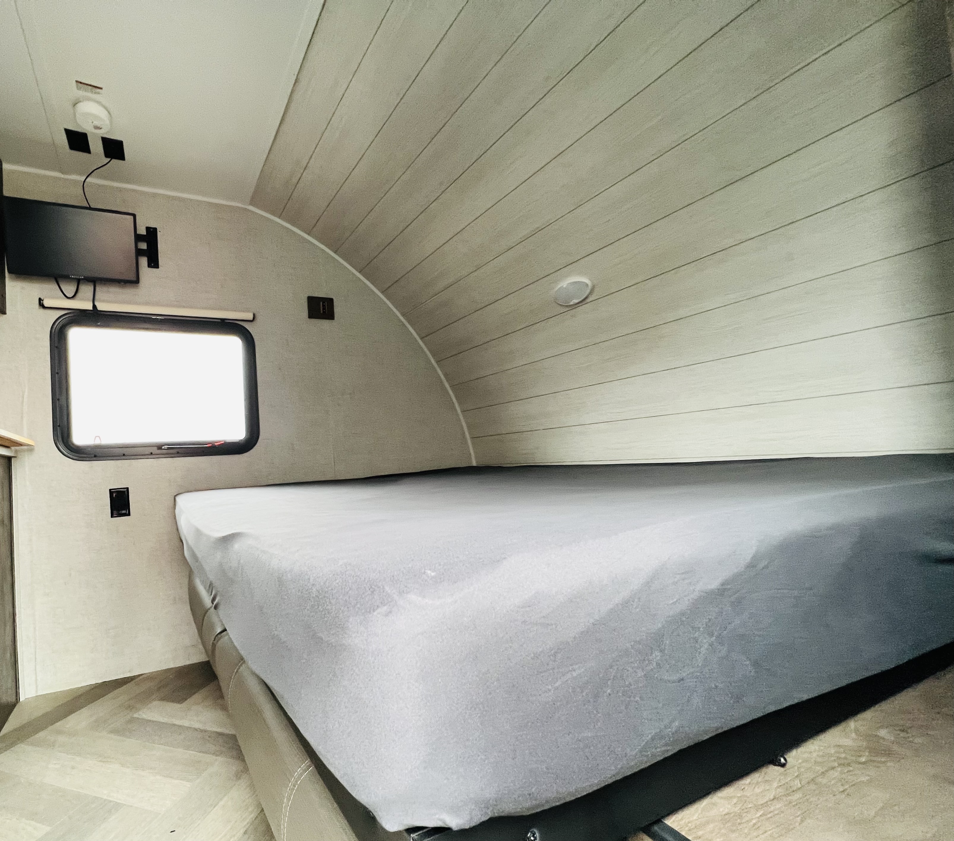 Inside an rv rental: a cozy bedroom with a large bed, TV, window, and distinct curved ceiling. Perfect for your next trip.. Forest River Salem 2020